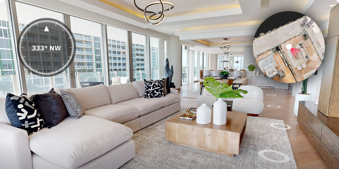 Moderne, helle Wohnung mit großen Fenstern, Sofa, Couchtisch mit Dekorationen, Esstisch im Hintergrund, Designer-Leuchten an der Decke, große Topfpflanzen, Stadtansicht durch die Fenster.