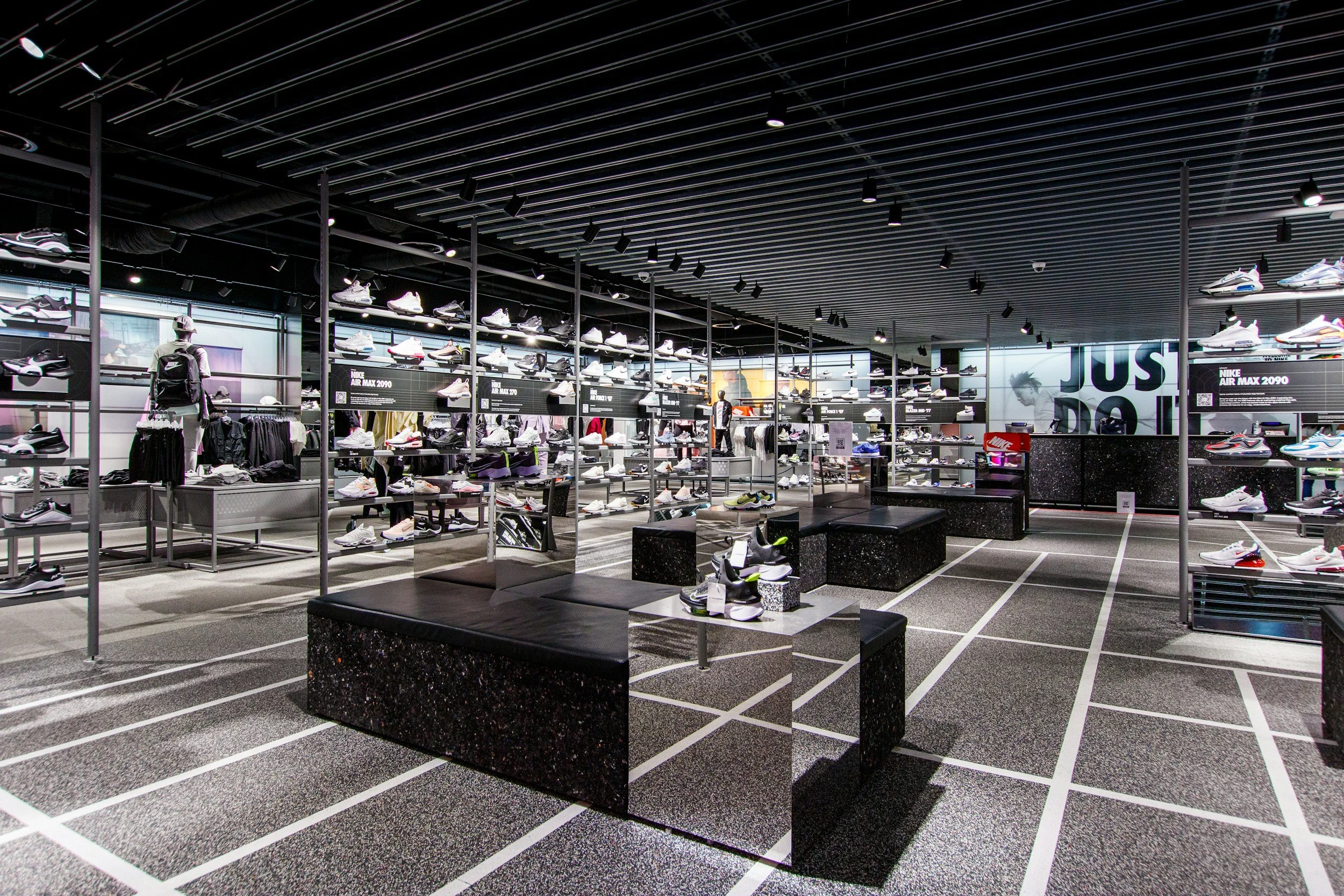 Innenansicht eines athletic stores, mit Regalen voller Sportschuhe und Sportkleidung, moderne schwarze Möbel und Beleuchtung, leerer Verkaufsraum.