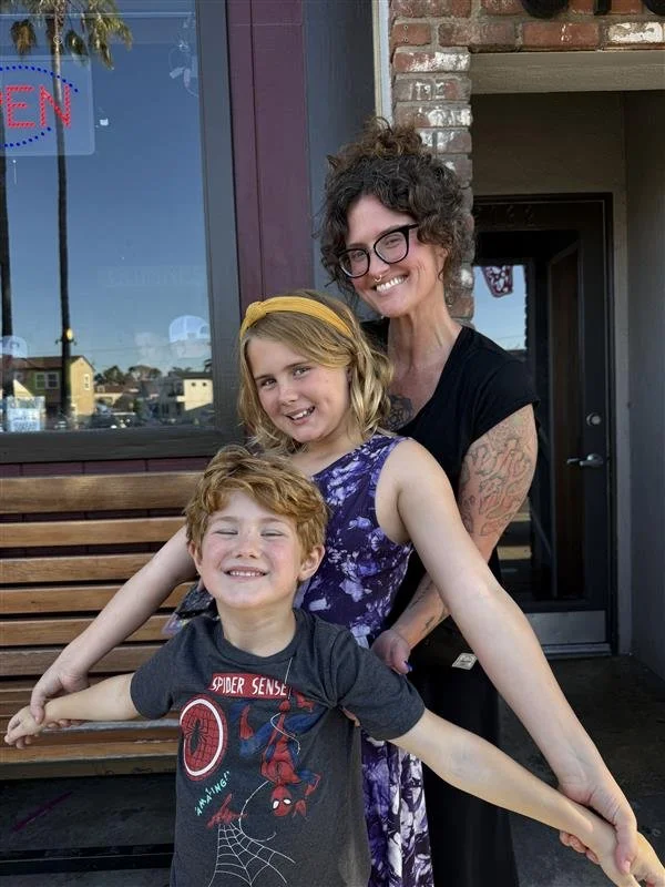 Smiling mother in glasses with two children outside