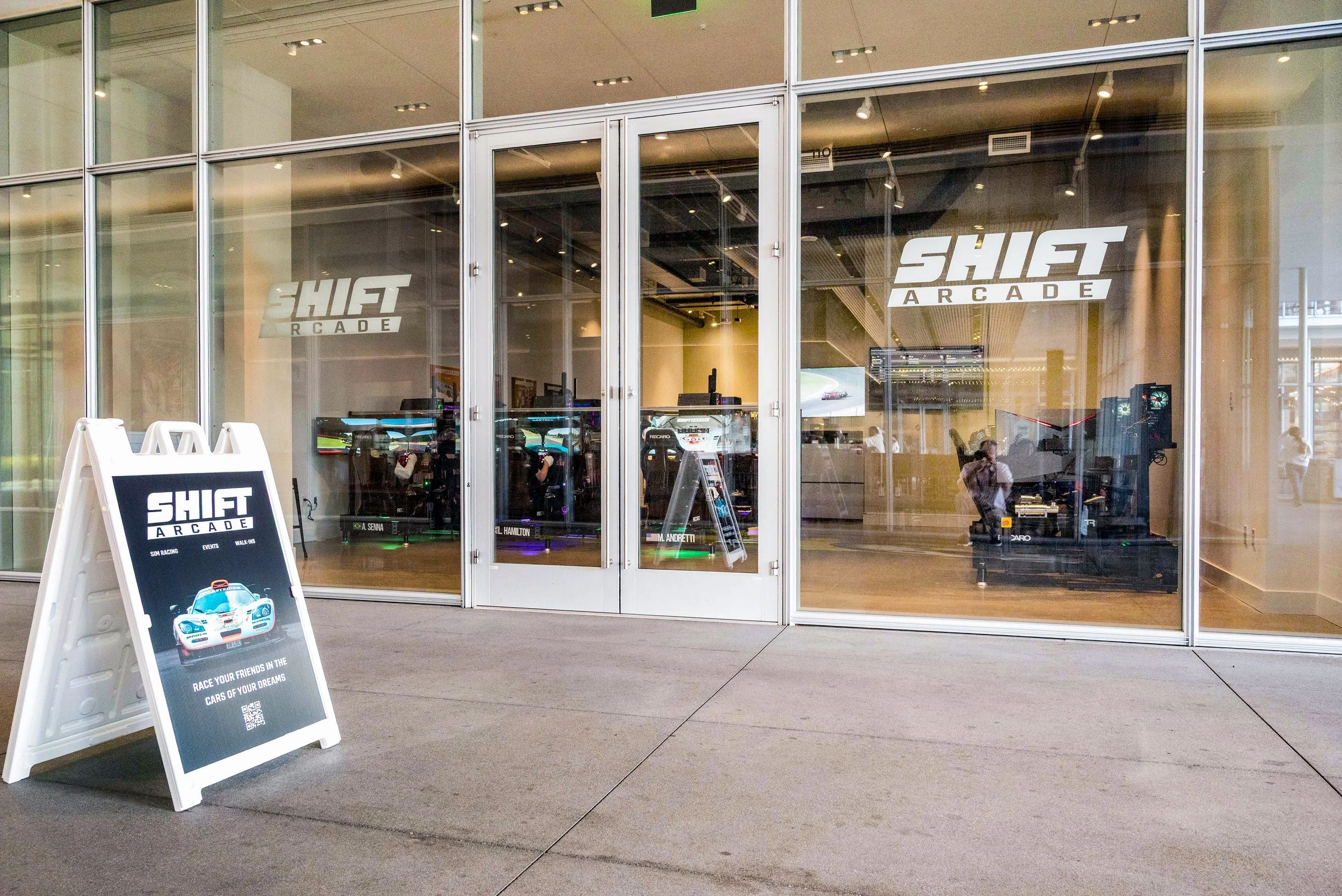Entrance of Shift Arcade with glass doors and a signboard displaying promotional content.