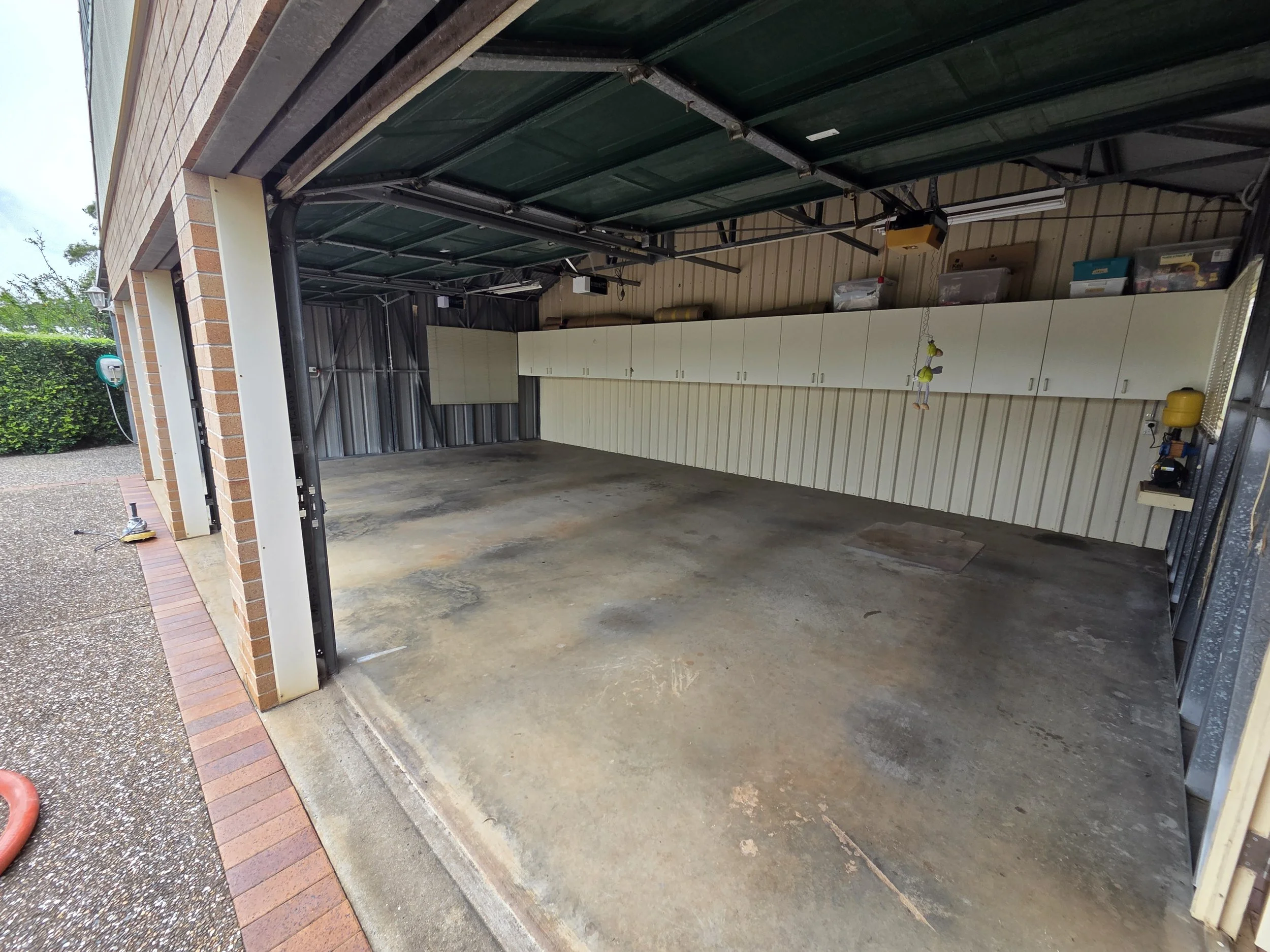 Empty garage with storage cabinets along the back wall and a concrete floor.