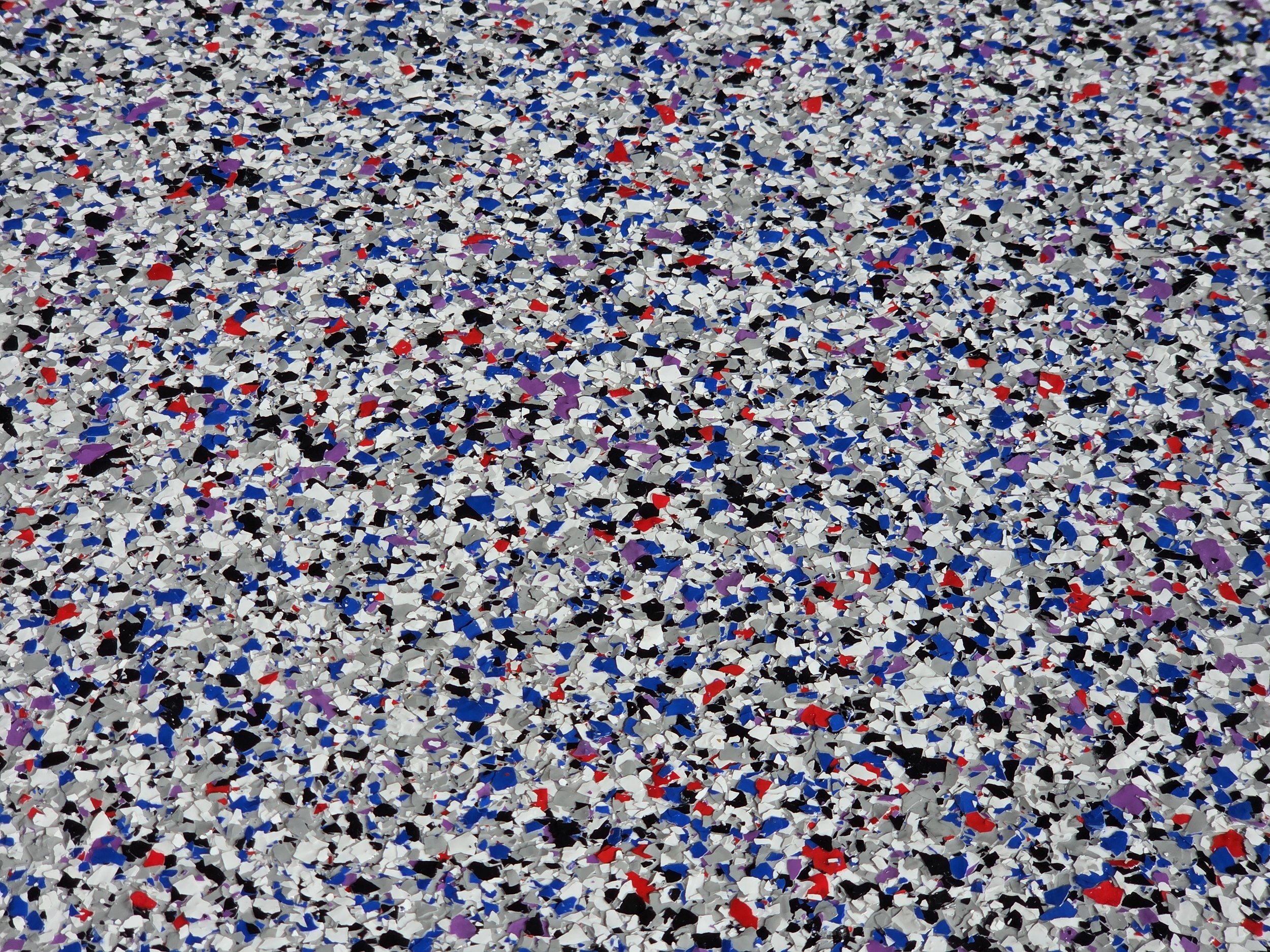 Close-up view of multicolored shredded paper, predominantly white with scattered pieces of red, black, blue, and purple.