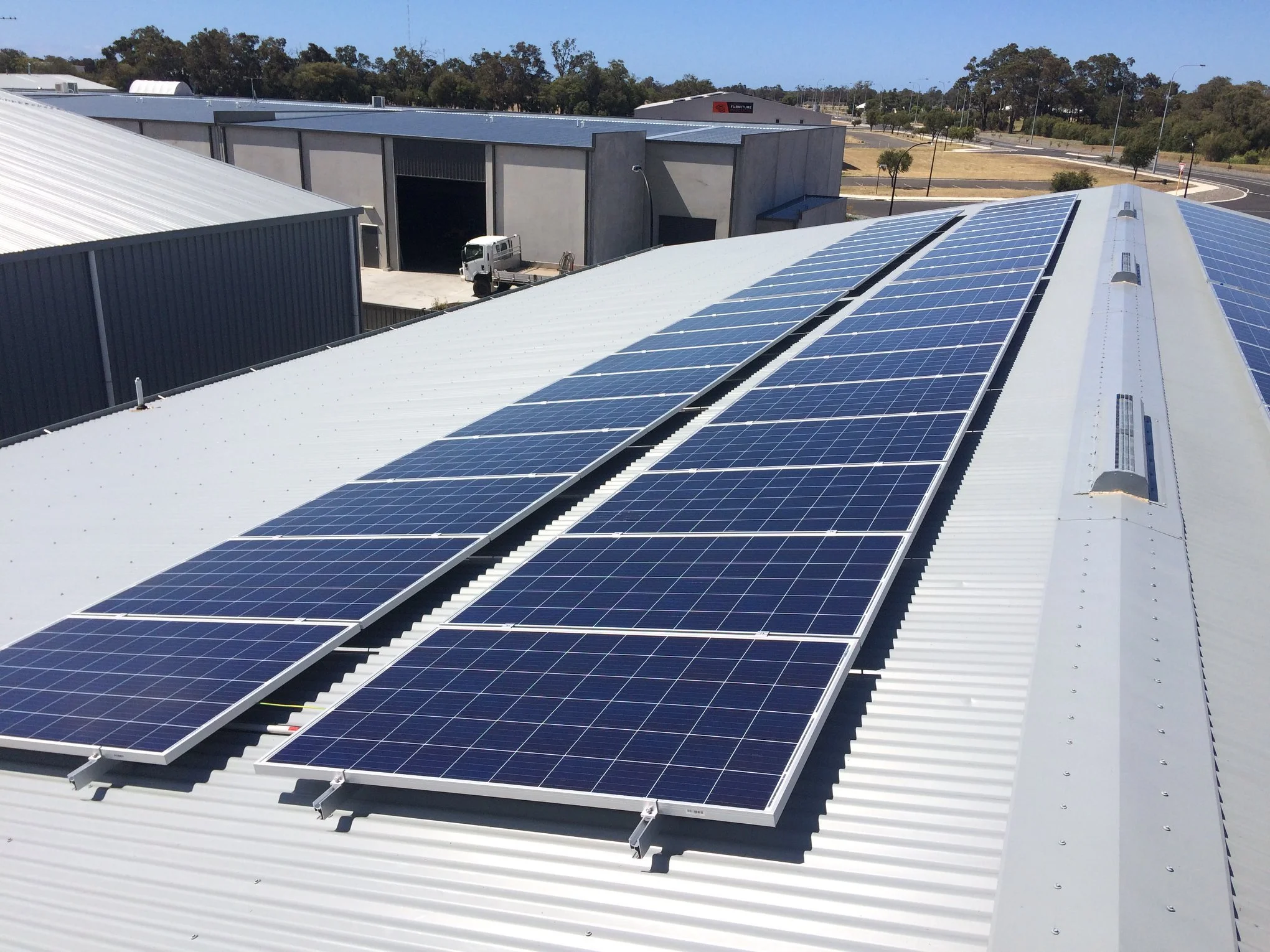 Solar panels installed on a white metal roof of a commercial or industrial building.