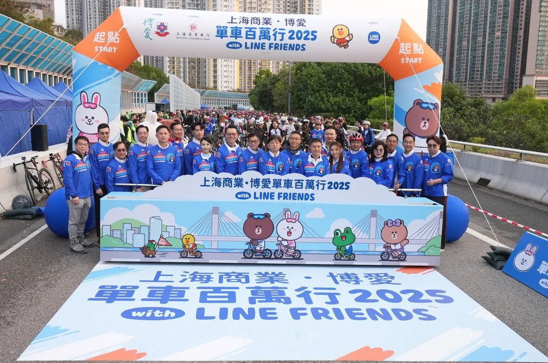 喺上海嘅一個單車活動，一班着住藍色外套嘅人企喺起跑拱橫額下面，上面有卡通動物角色同城市景觀藝術品。