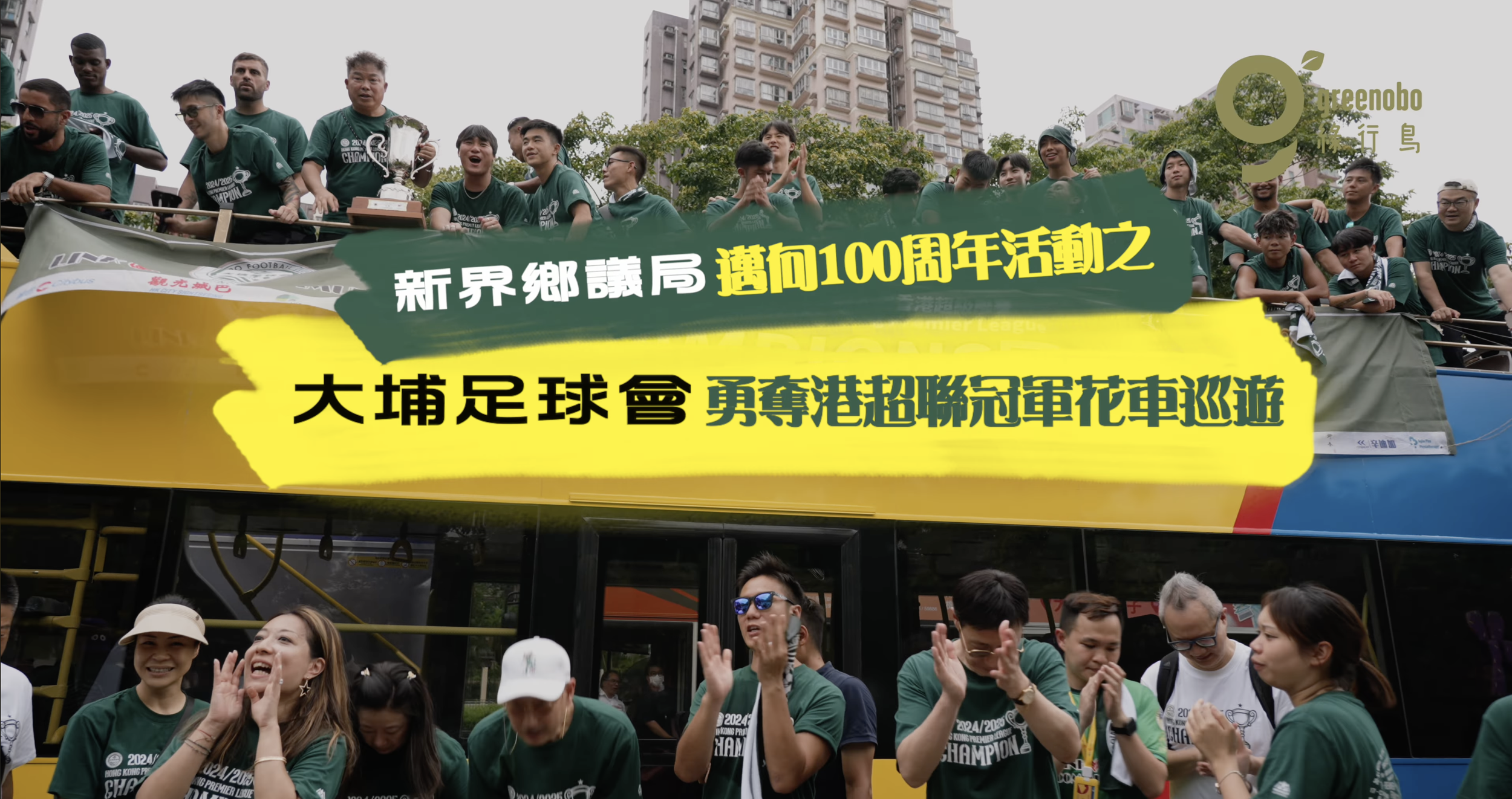 喺一個有高樓同樹木嘅市區，一班人喺一架雙層巴士上面，上面掛住一條橫額，上面寫住中文文字，慶祝緊一場運動勝利，全部都着住綠色衫。