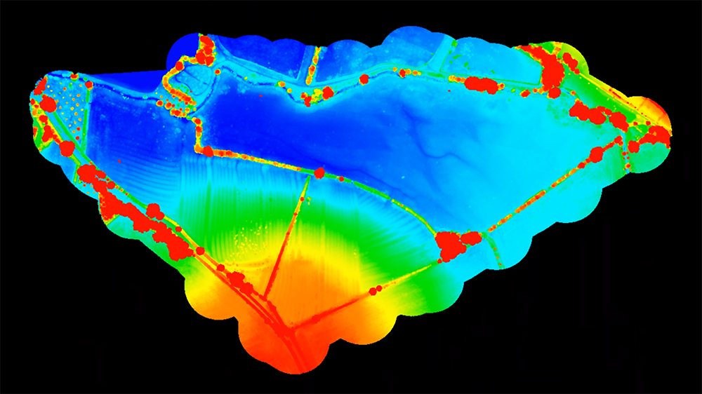 Color-coded map of a rectangular surface with various markings, lines, and red spots, possibly representing data points or areas of interest.