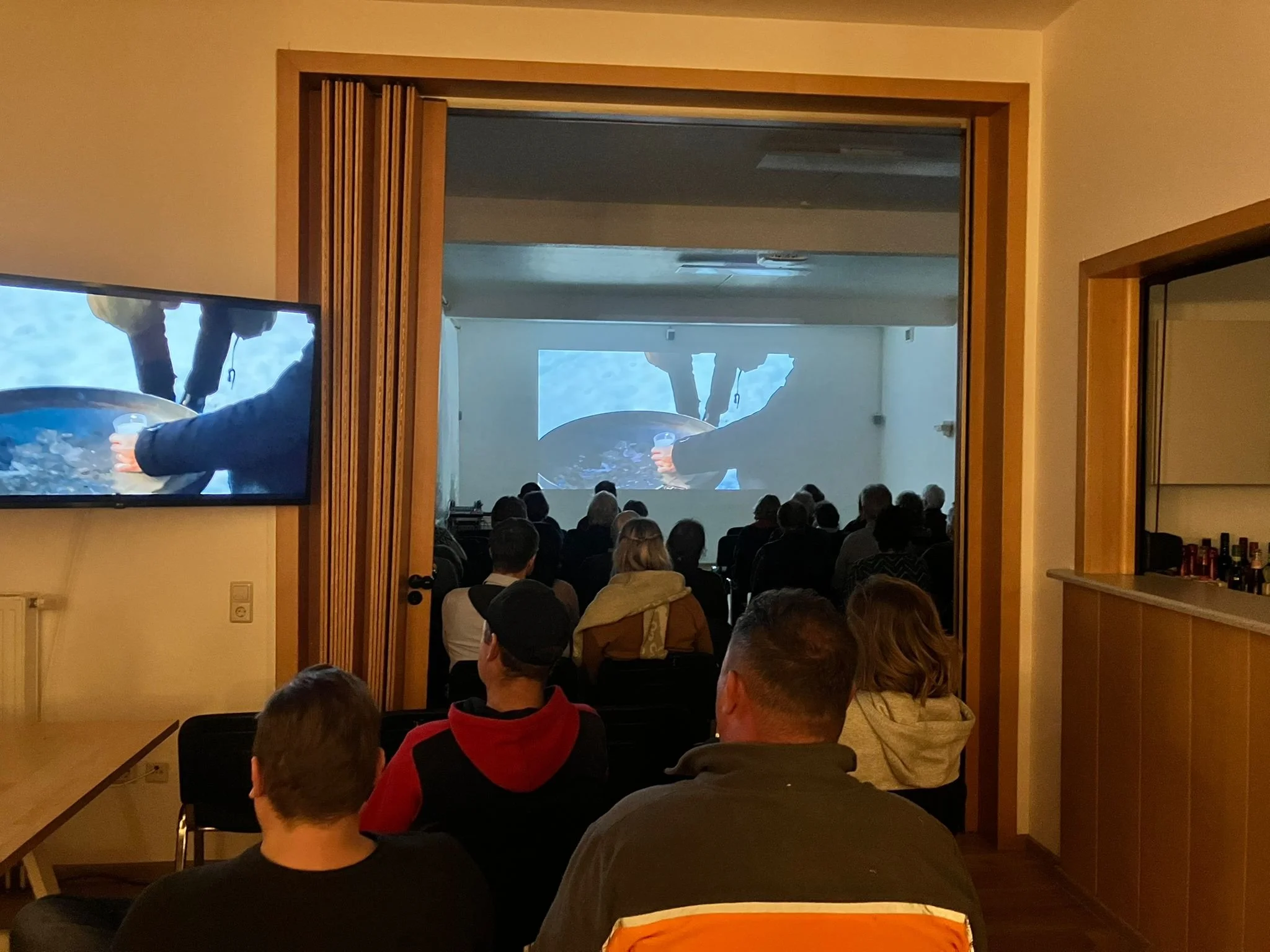 Der volle Saal des Gemeindehauses schaut auf die Leinwand