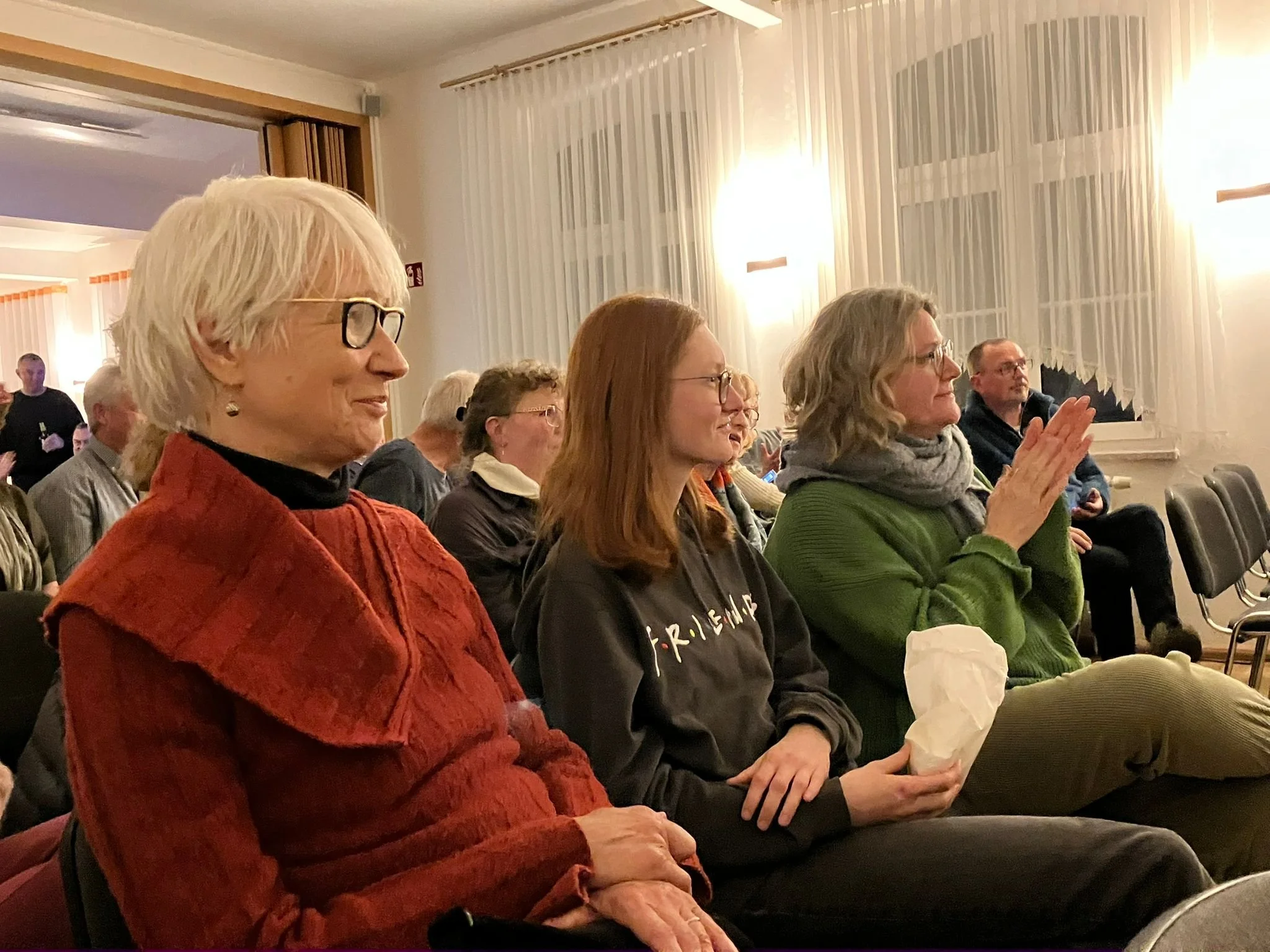 Publikum der Veranstaltung lächelt in die Kamera