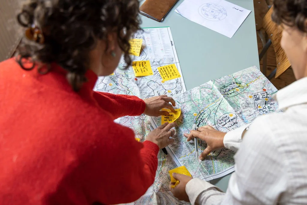 Twee mensen die samenwerken aan een routekaart met post-its en aantekeningen.