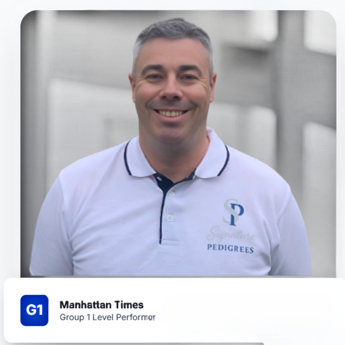 A smiling man in a white polo shirt with the logo and text 'Signature Pedigrees' standing outdoors in front of a blurred background.