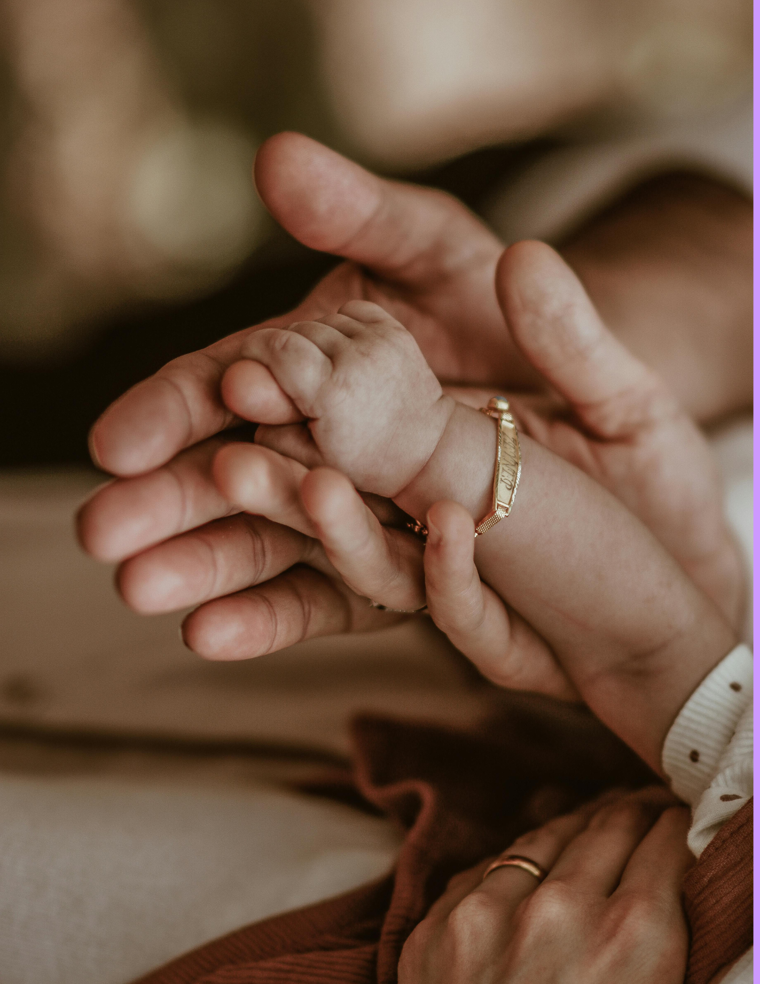 Close-up of an infant's hand holding an adult's finger, both wearing rings.