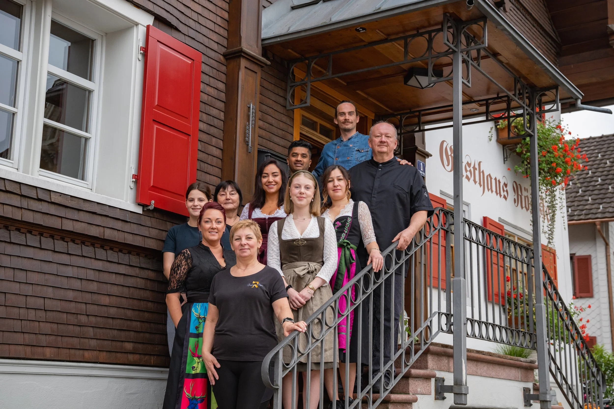 Gruppenfoto von Menschen vor dem Gasthaus Rössle auf einer Außentreppe stehend.