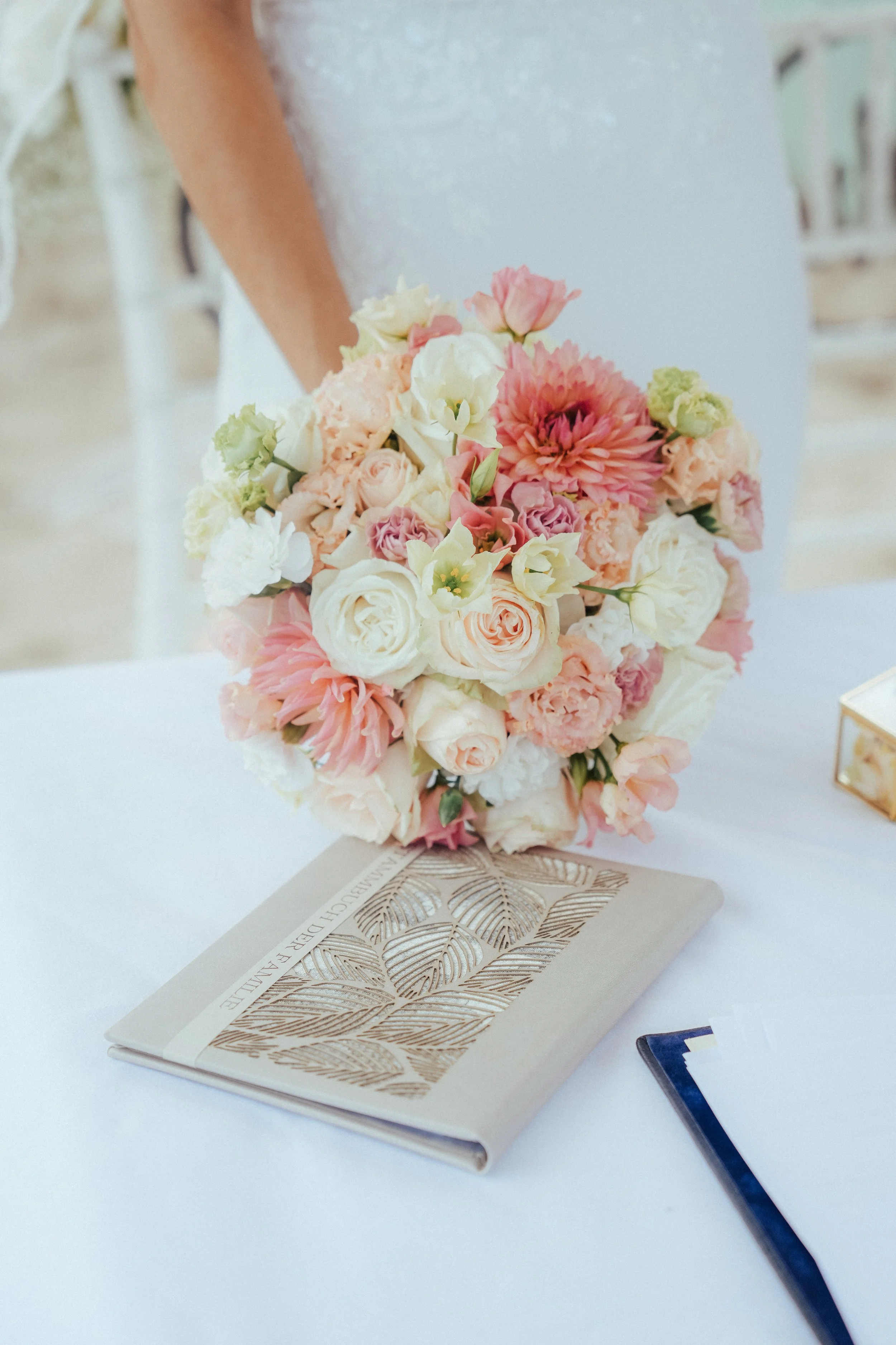 Blumenstrauß mit rosafarbenen und weißen Blumen auf einem weißen Tisch neben einem Buch und einem kleinen goldfarbenen Schatzkästchen Kiel und Flintbek
