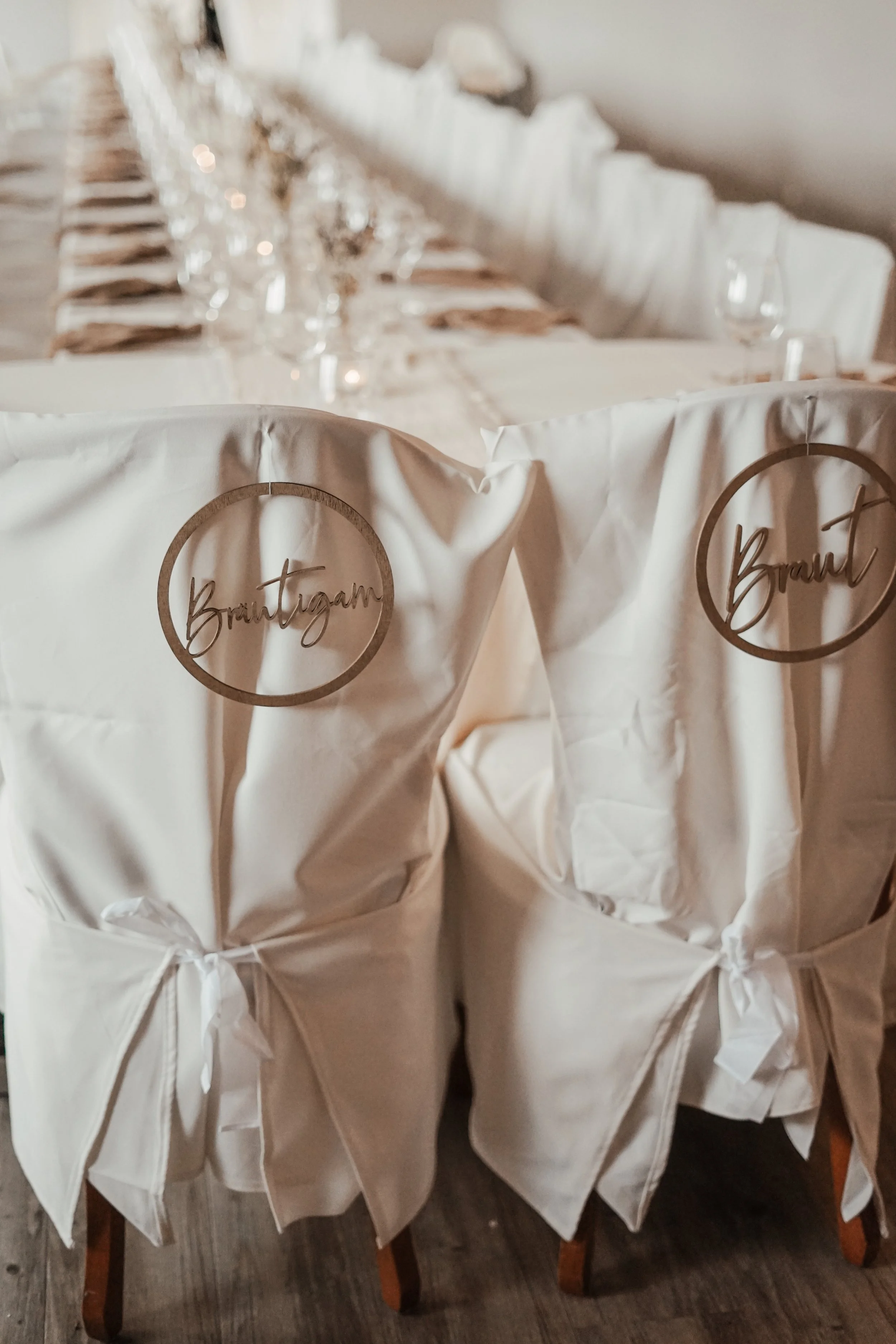 Stühle bei einer Hochzeitsfeier mit weißen Stoffüberzügen und Namensschildern, die 'Brautpaar' heißen Kiel und Flintbek