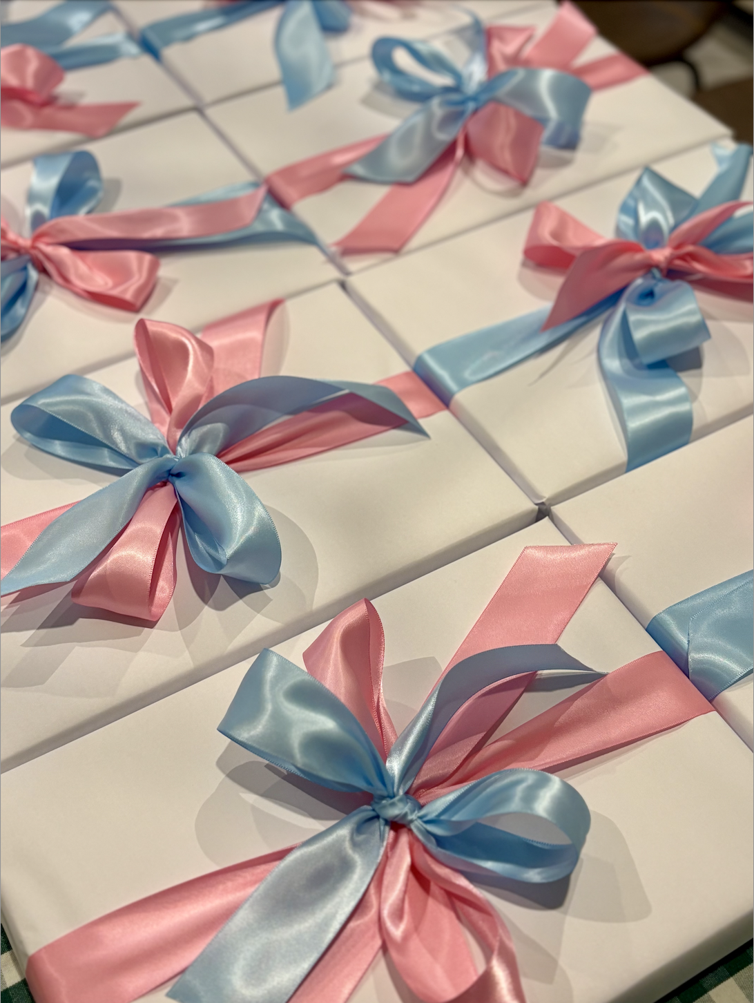 White gift boxes decorated with pink and blue satin ribbons tied into bows | Luxury Gift Wrapping & Custom Hampers