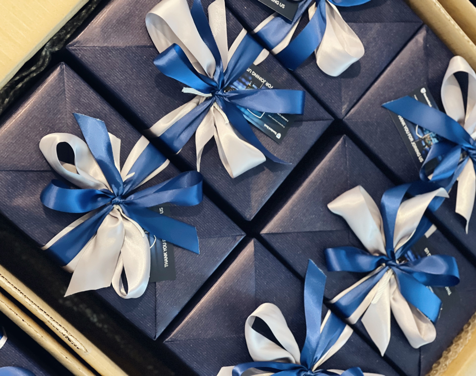 Several navy blue gift boxes wrapped with white and navy blue ribbons with bows, inside a cardboard box | Luxury Gift Wrapping & Custom Hampers