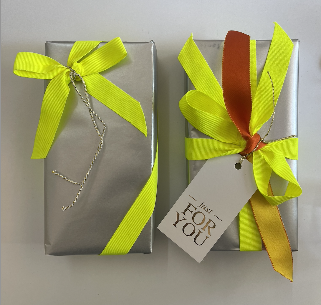 Two silver gift boxes wrapped with yellow ribbons and bows, one with an orange ribbon, and a tag that says "just for you" | Luxury Gift Wrapping & Custom Hampers.