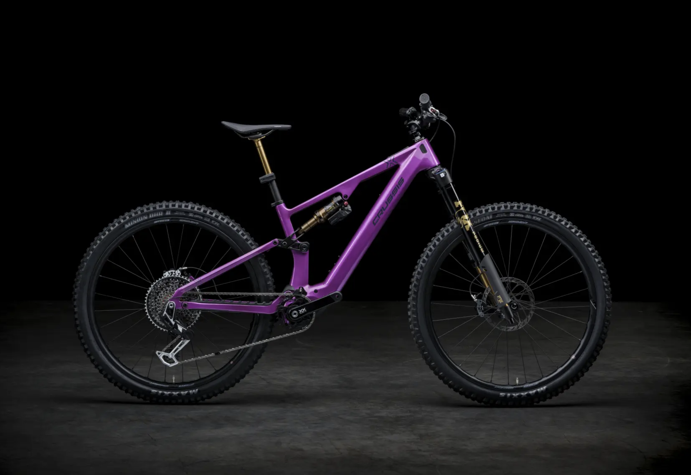 Ein pinkfarbenes Mountainbike mit goldfarbenen Federungen vor einem schwarzen Hintergrund.