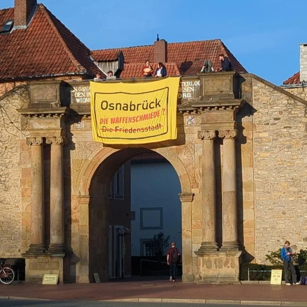 Das Waterloo-Tor von Osnabrück mit einem großen Transparent auf dem steht "Osnabrück Die Waffenschmiede?" und "Friedenstadt (durchgestrichen)"