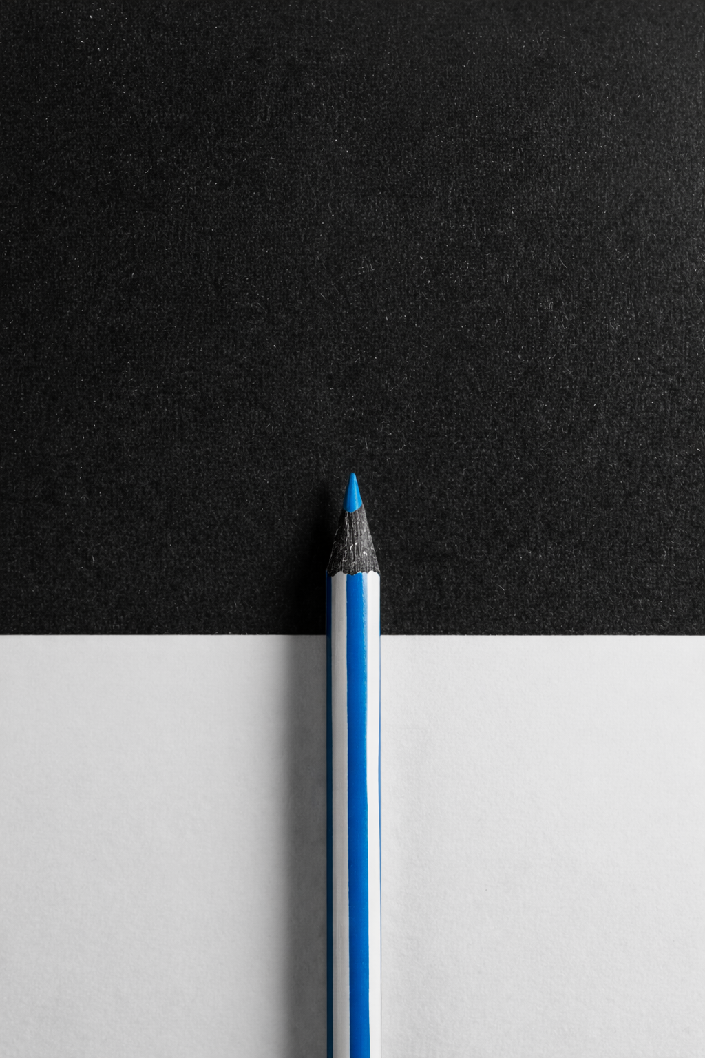 Foto bianco nero con foglio su tavolo di grafite e matita a colori blu e bianco come unico elemento colorato