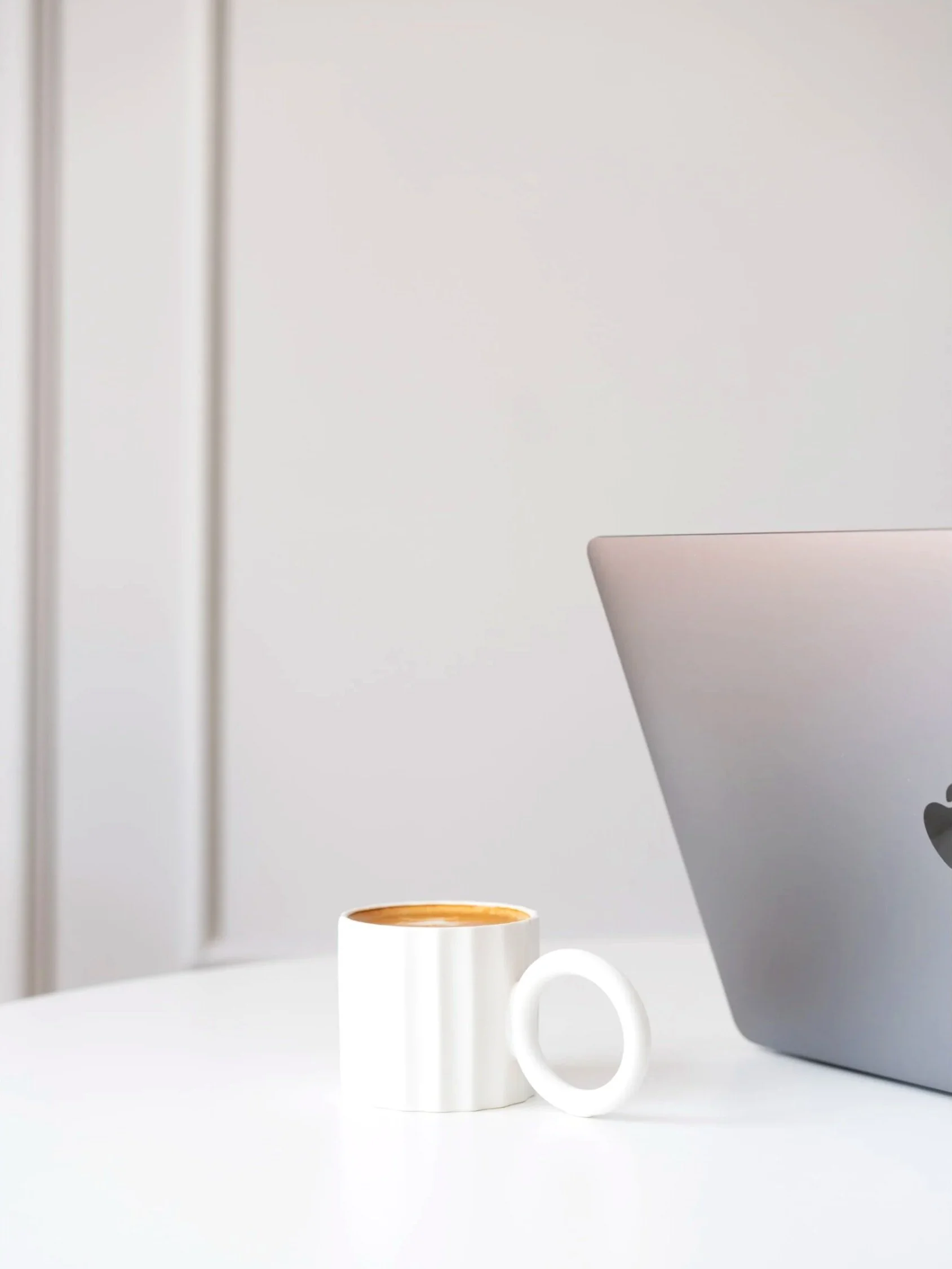 Kaffeetasse auf weißem Tisch neben Laptop