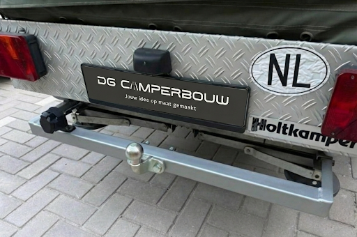 Achterzijde van een voertuig met een trekhaak en een inscriptie 'DG Camperbouw'.