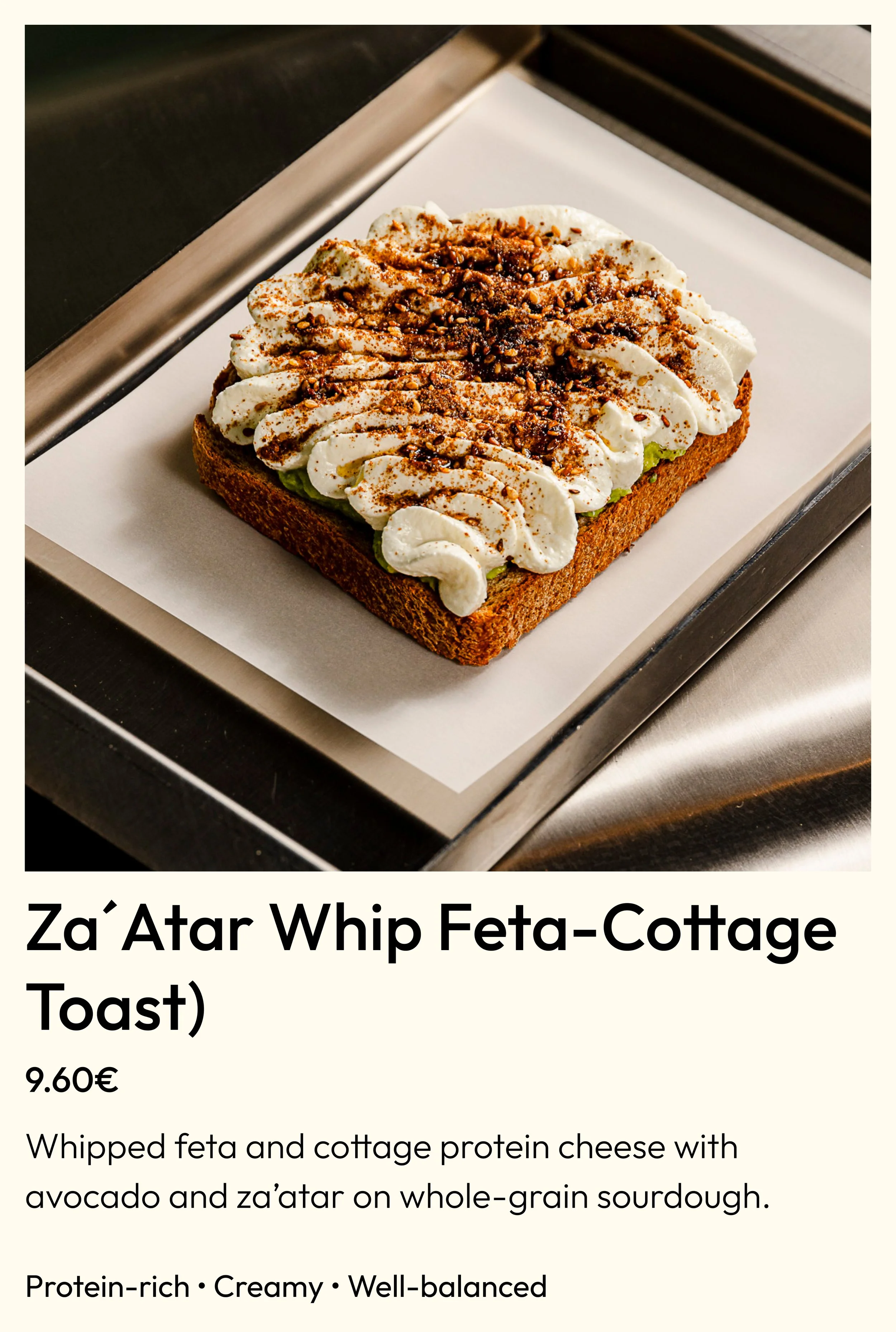 Close-up of Za’atar Whip Feta-Cottage Toast on a white paper-lined tray, topped with whipped feta, cottage cheese, avocado, za’atar, and crushed nuts or seeds.