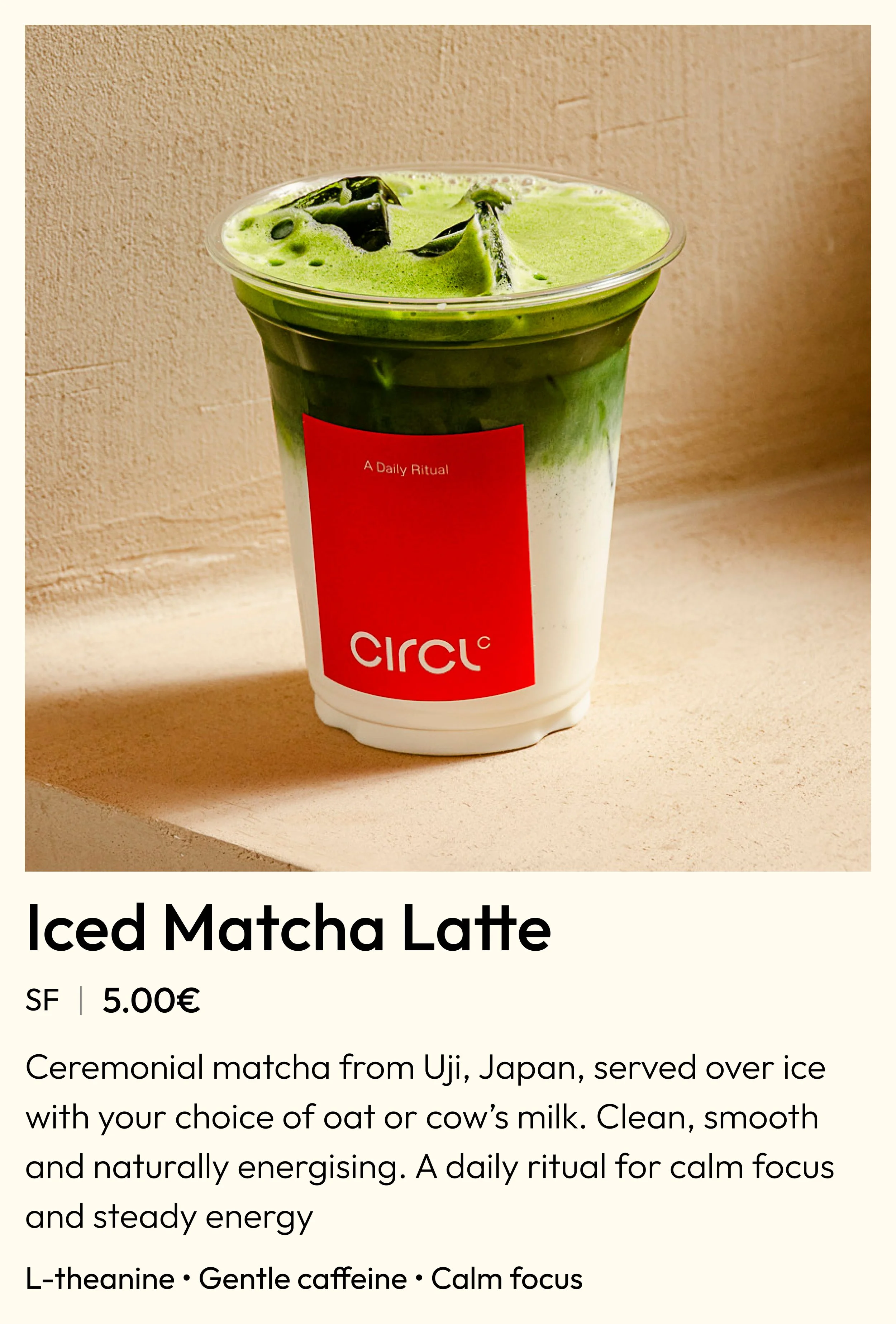 A clear plastic cup filled with iced matcha latte, with a layer of green matcha on top of white milk, with ice cubes visible on top.