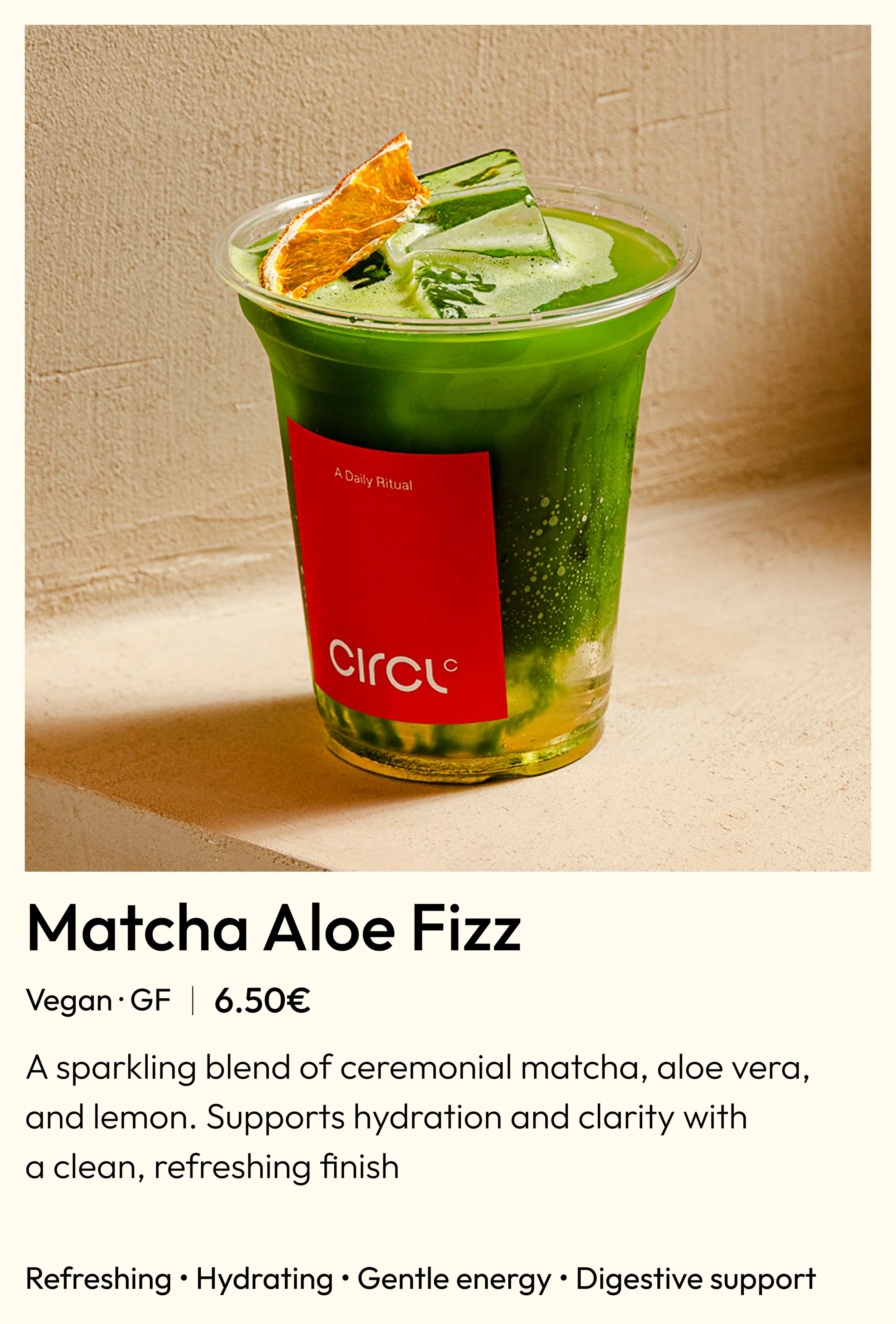 A clear plastic cup of Matcha Aloe Fizz with green matcha, aloe vera, and lemon slices on top, placed on a light-colored surface with a beige background.