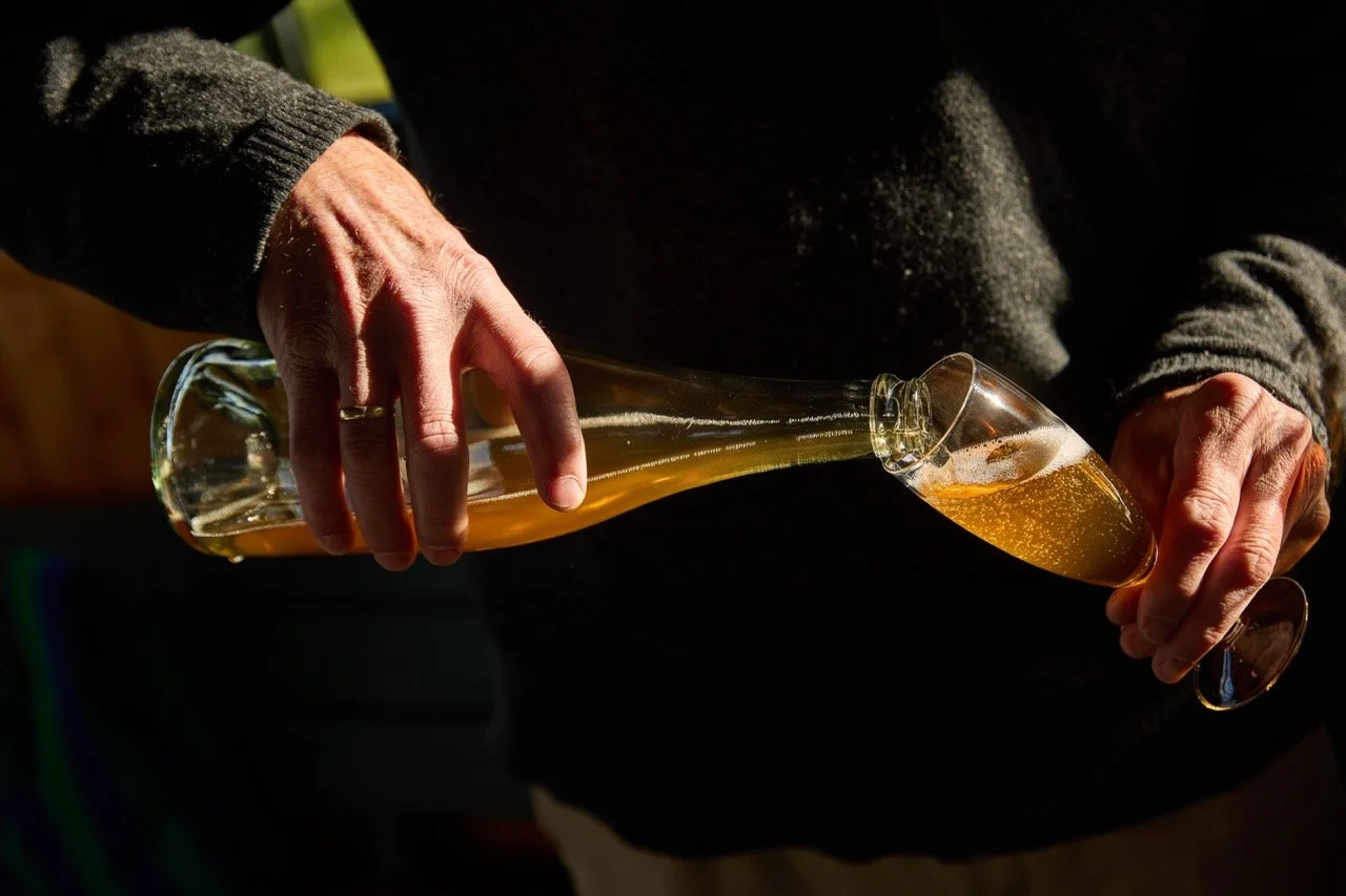 Person som heller drikke fra en ølflaske til et vinglass.