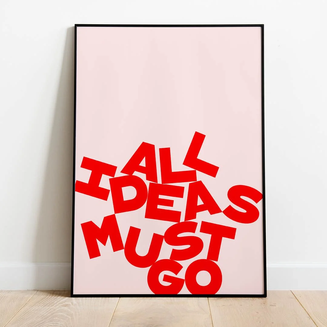 Framed poster with the phrase "ALL IDEAS MUST GO" in bold, jumbled red letters against a pale pink background.