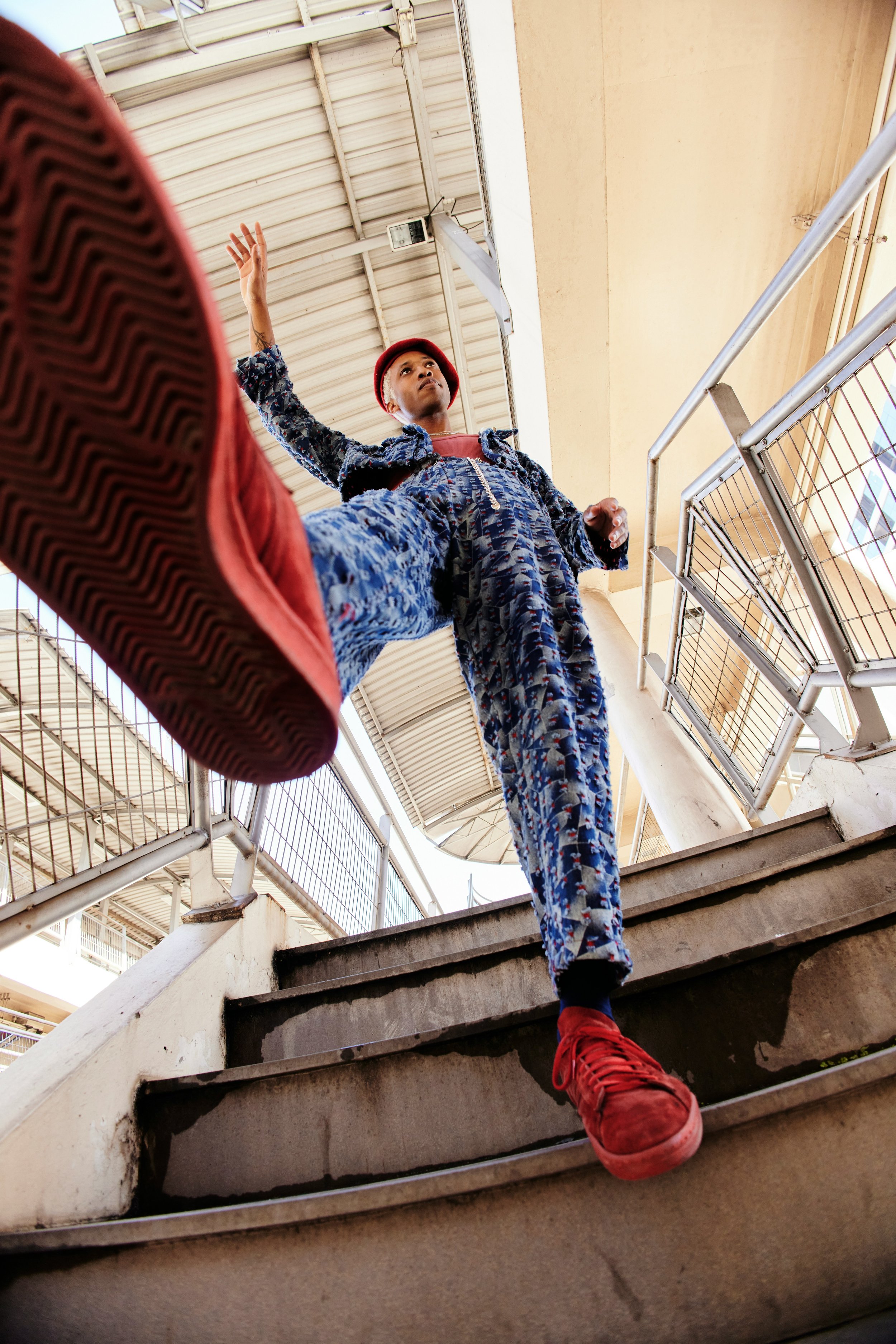 Person wearing a red hat and patterned blue outfit walking up stairs taken from below