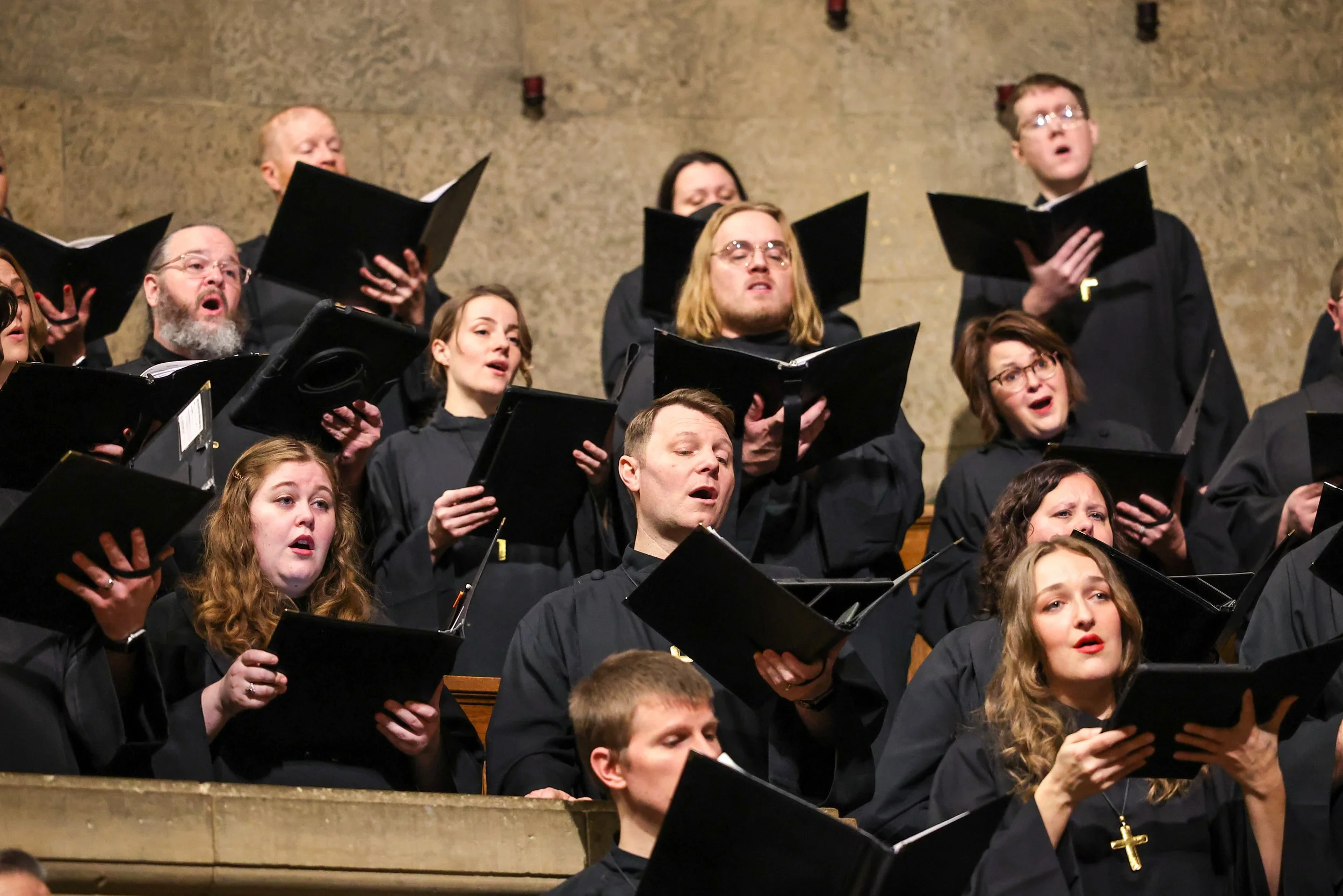 Group of singers from National Lutheran Choir holding folders and singing