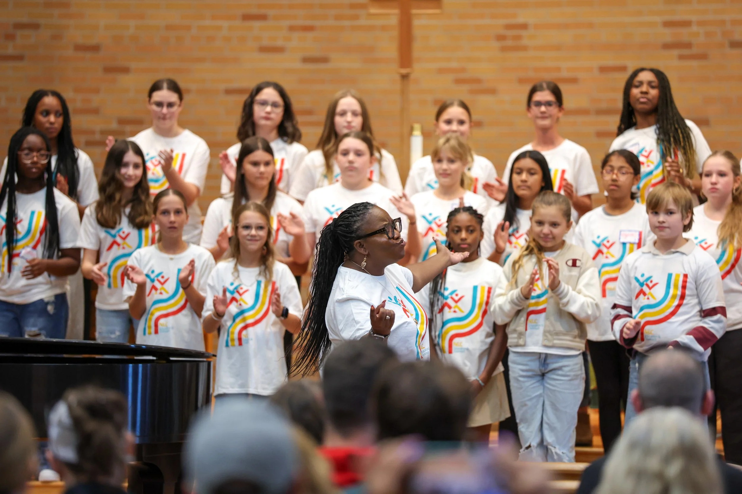 A group of younger singers clapping to the beat under the direction of conductor Maria A Ellis