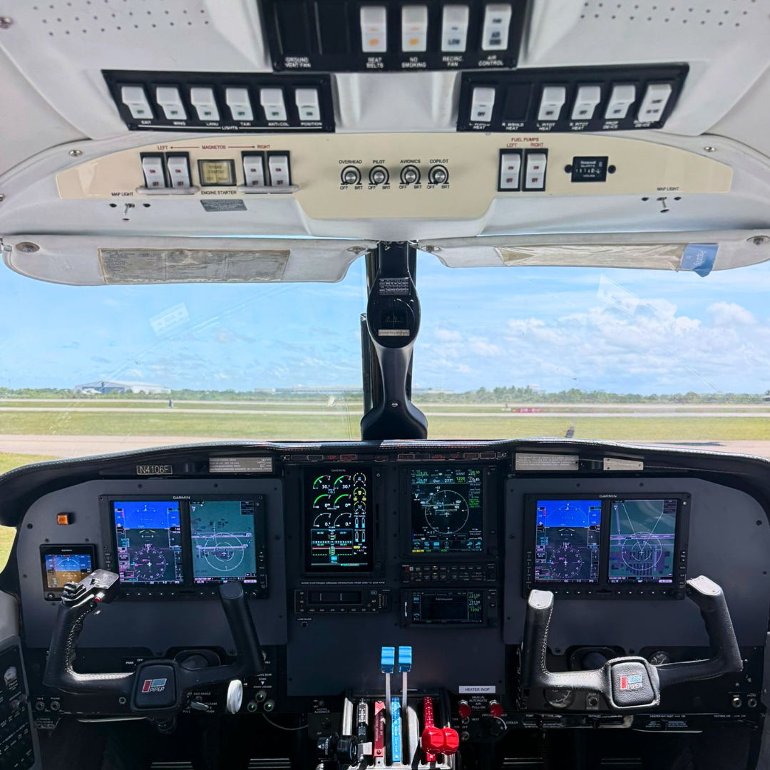 Cockpit of an airplane with instruments and controls, runway visible through windshield under a blue sky with some clouds.