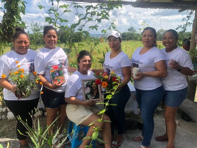 A photo of Miss Beatrice's family, holding a portrait of her along with her novel and flowers,