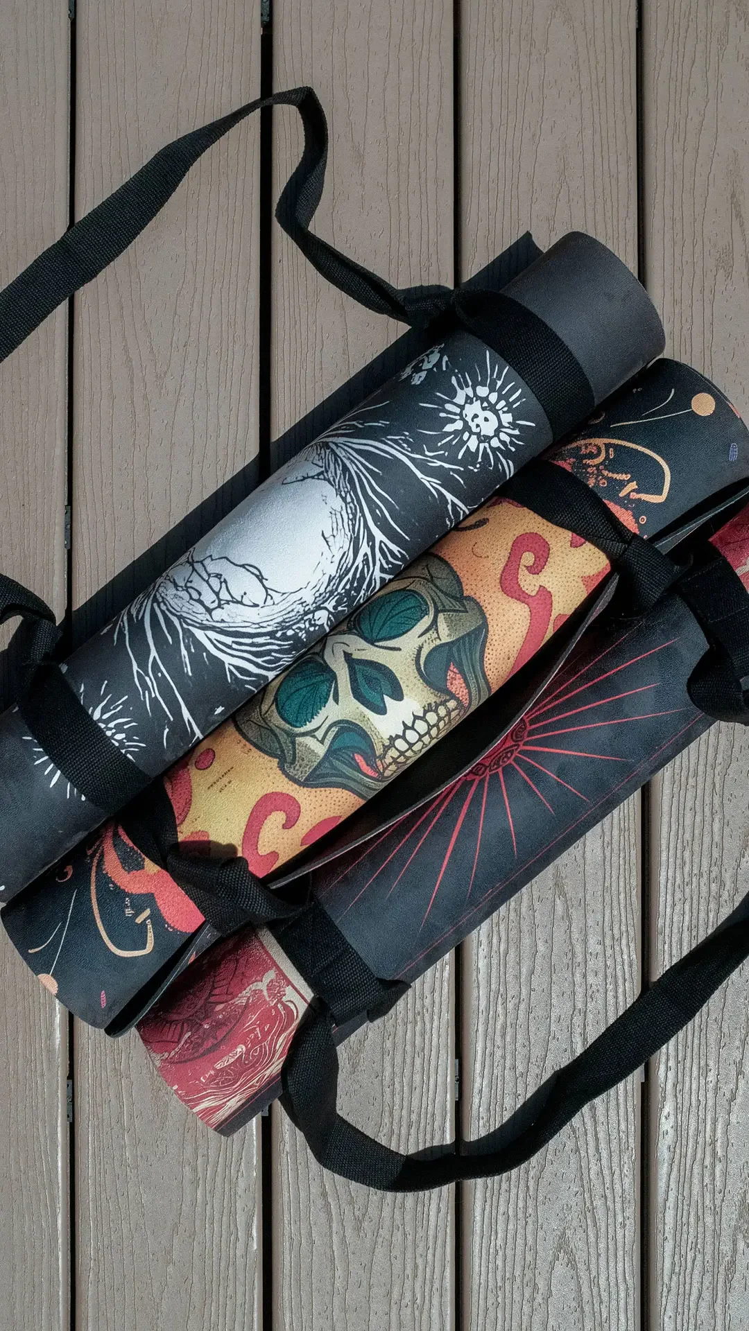 three metal-inspired yoga mats rolled up with carrying straps