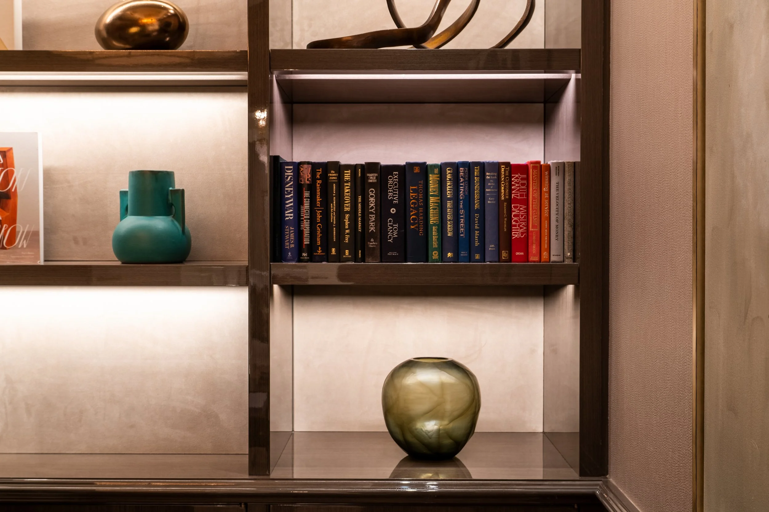 Bookshelf with books, a blue vase, and a decorative bowl.
