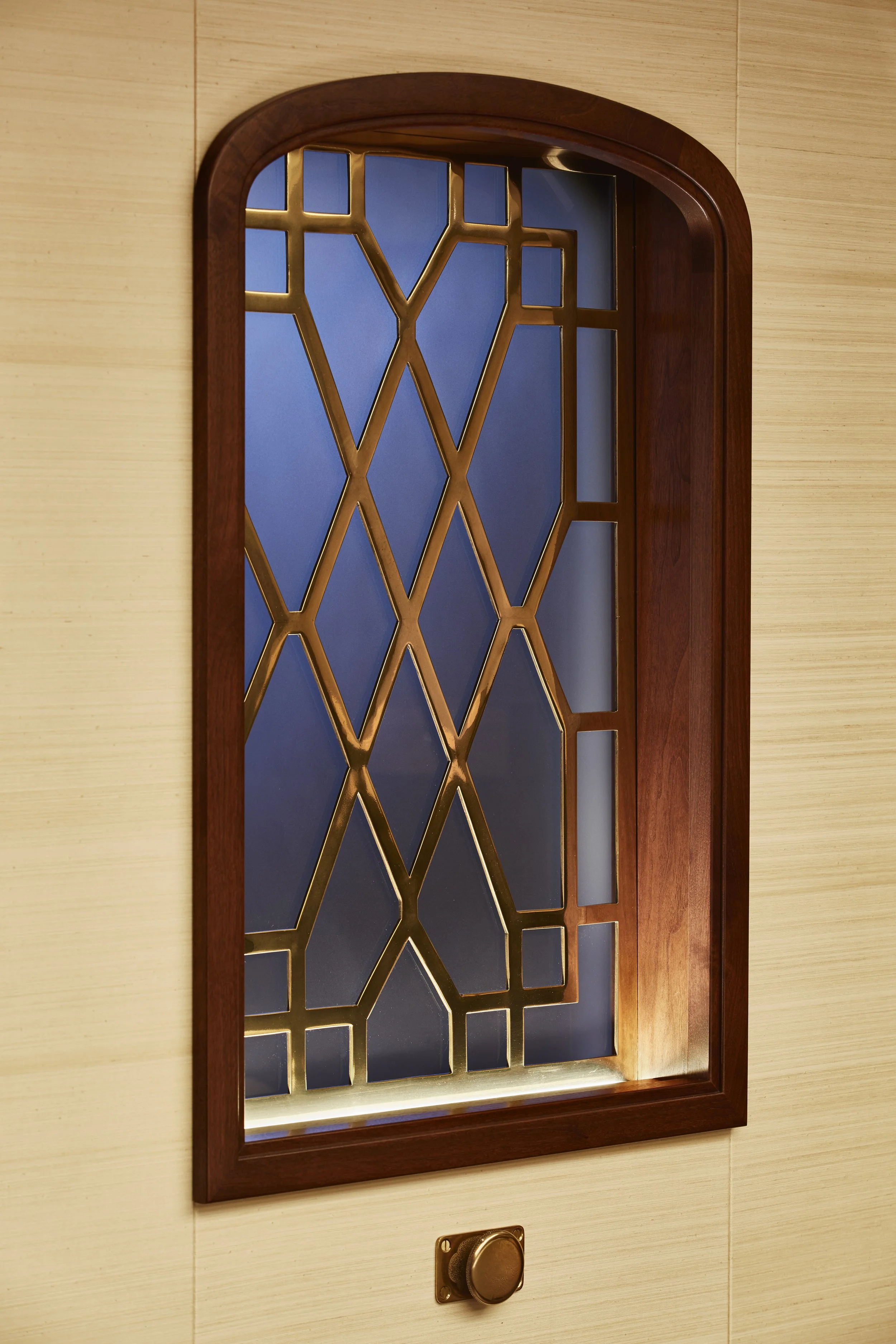 Decorative window with geometric metal grill and wood frame.