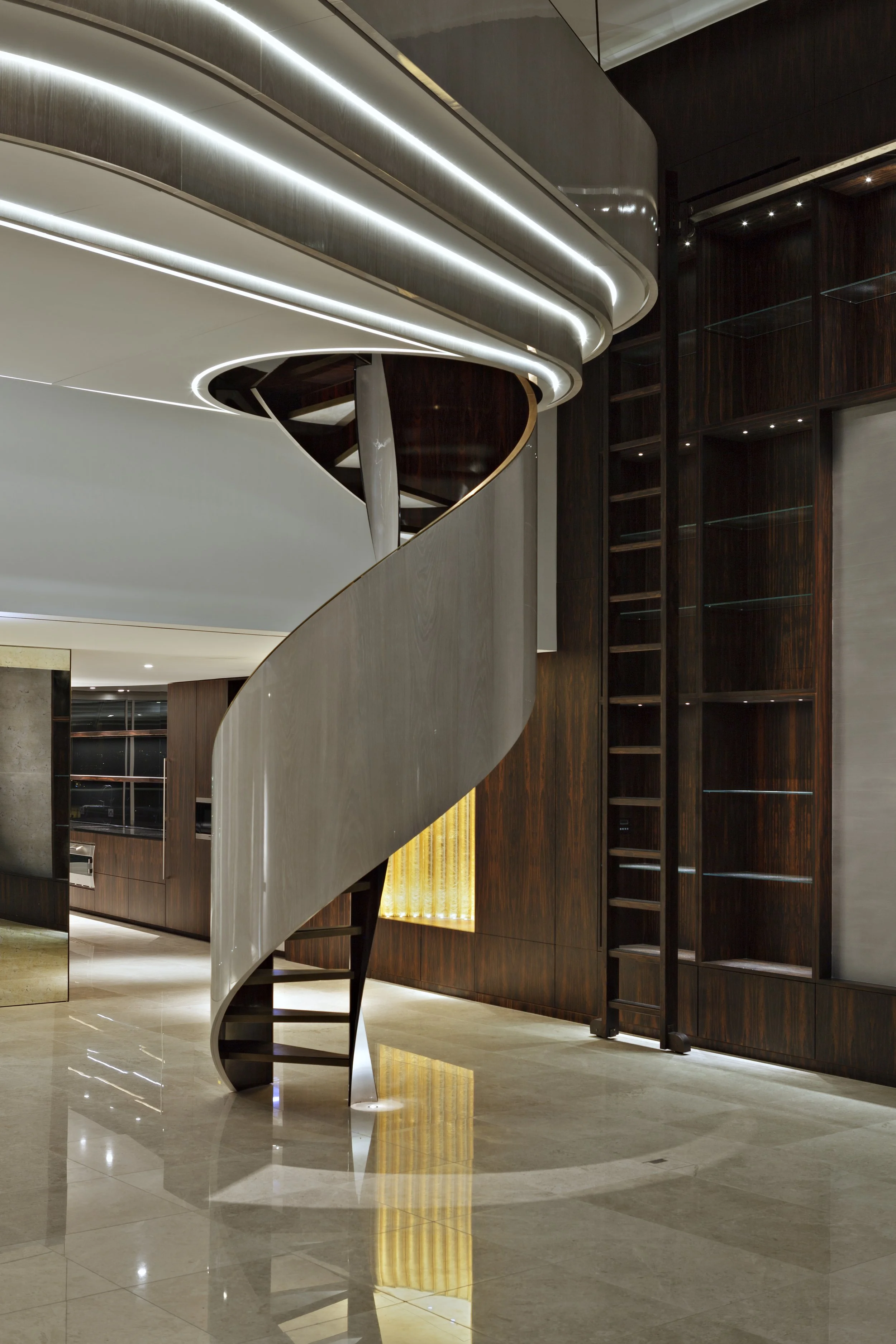 Modern interior with a sleek spiral staircase and reflective flooring, featuring dark wood accents and ambient lighting.