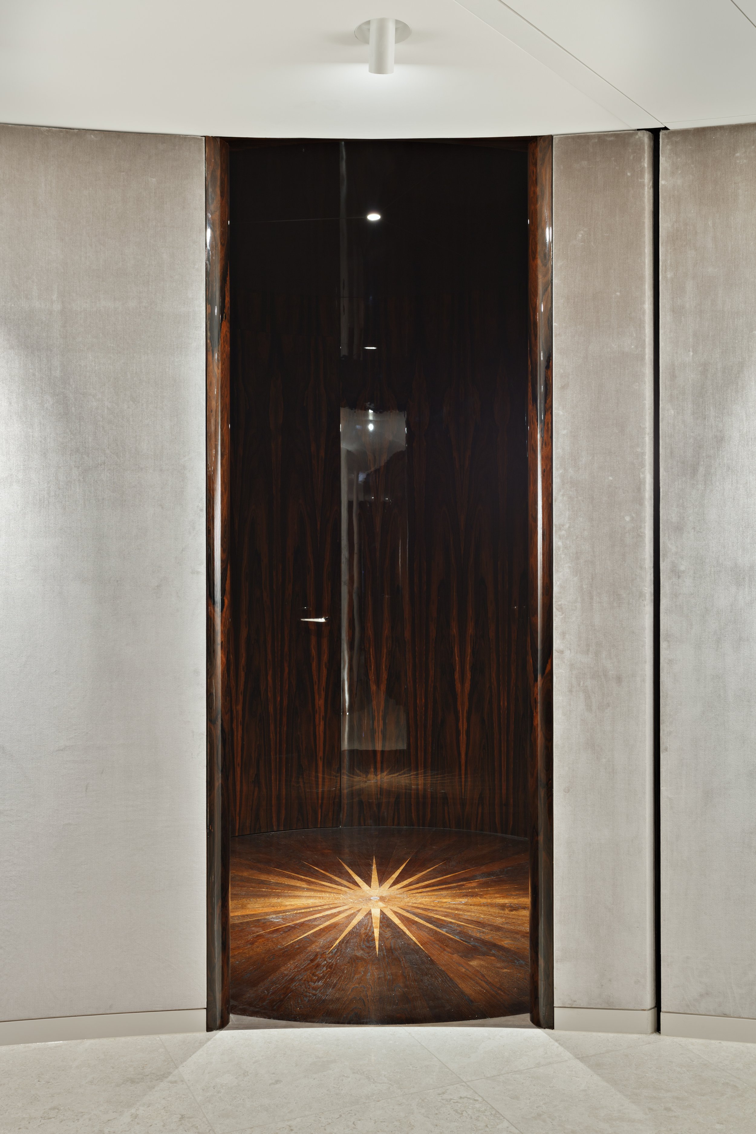 Wooden door in an interior space with a starburst design on the floor.