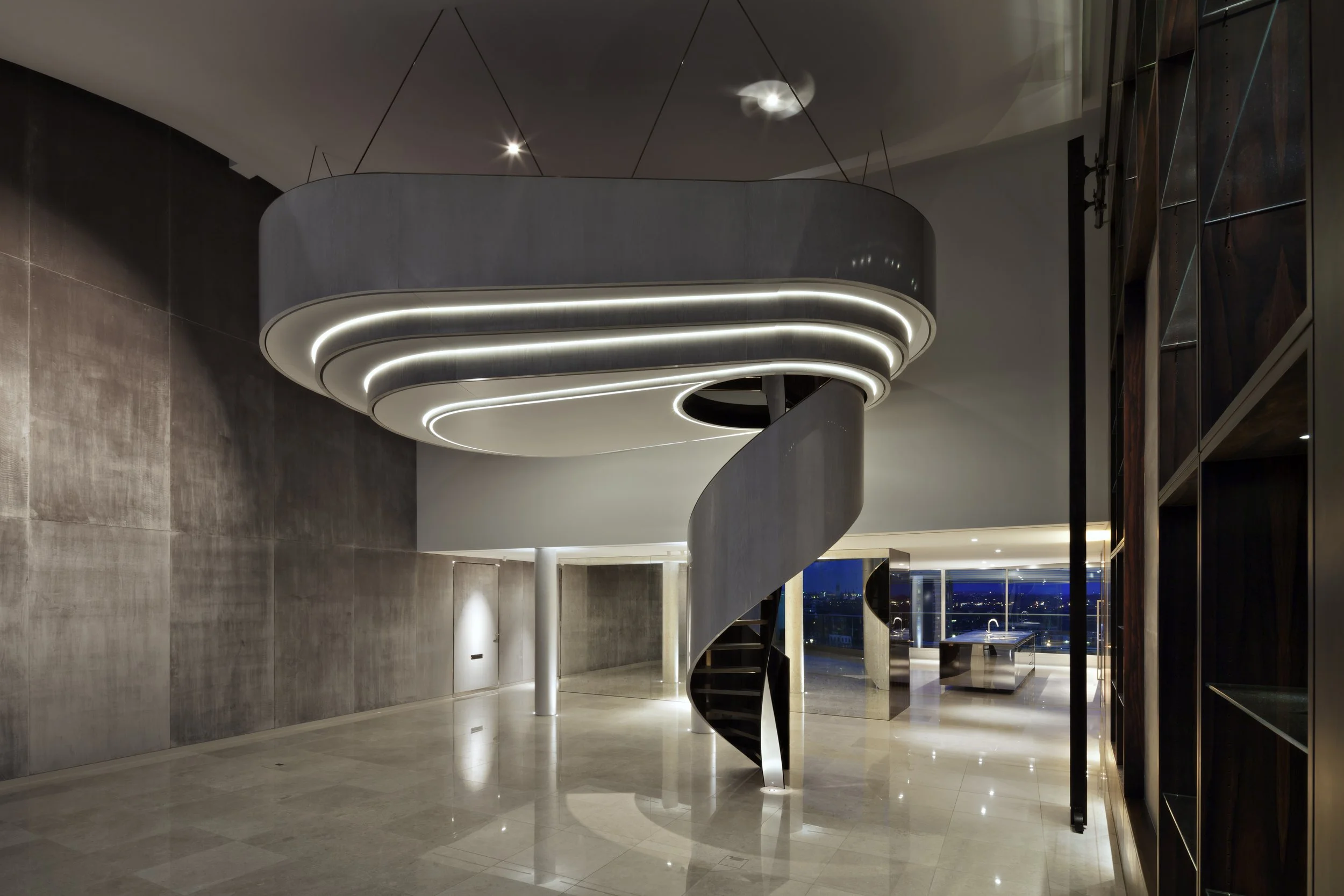 Interior of a modern, minimalist home with a spiral staircase and a suspended ceiling feature with integrated LED lighting.