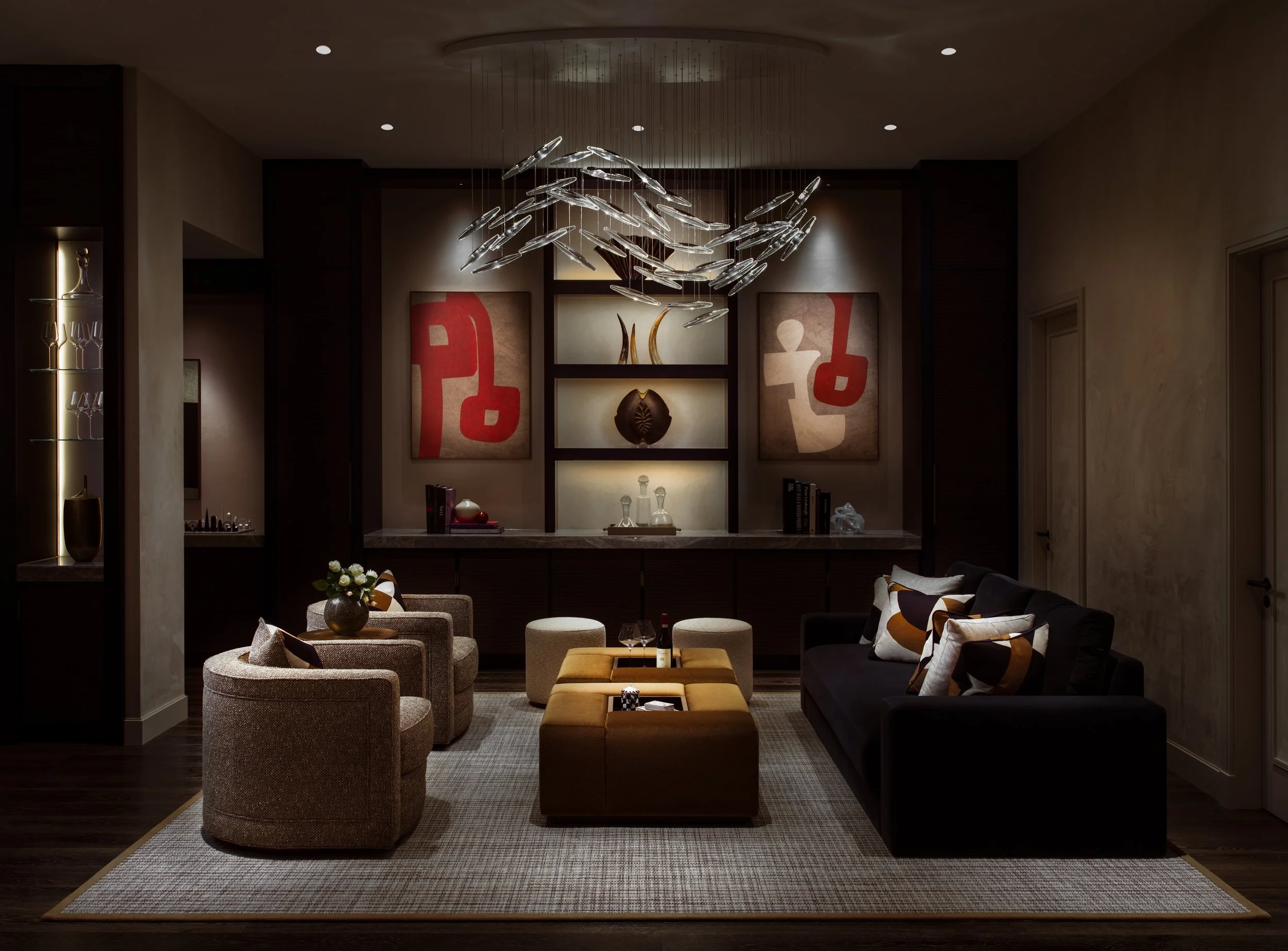 Elegant living room with a dark sofa, two armchairs, two ottomans, modern art on the walls, and a contemporary chandelier.