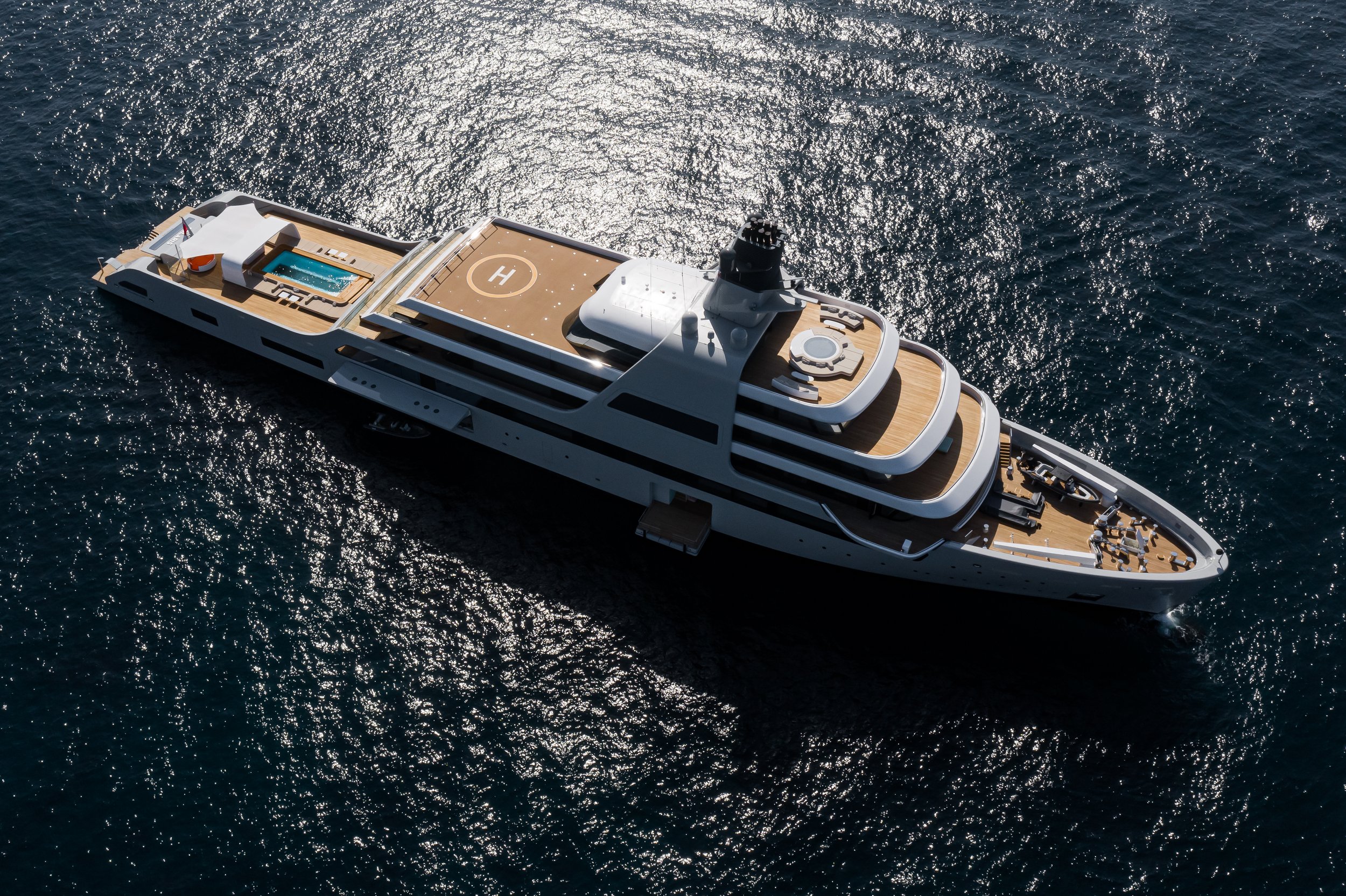 Aerial view of a luxury yacht with a helipad and pool on the water.