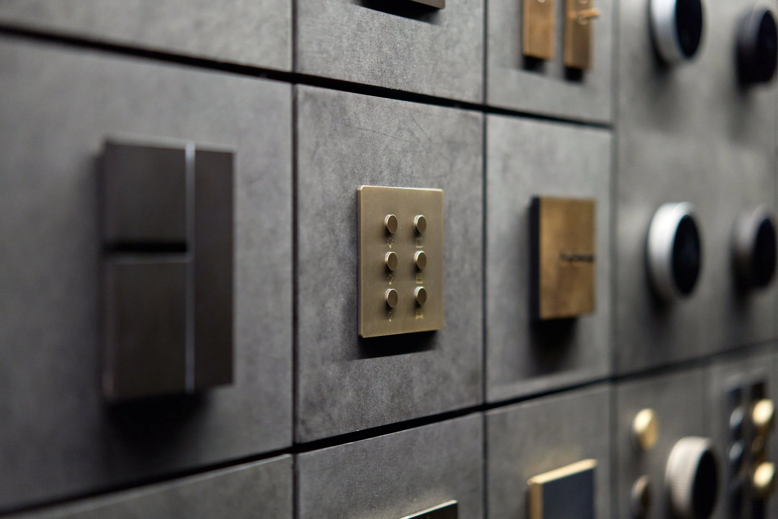 Close-up of a wall with various metallic and brass control panels, switches, and dials.