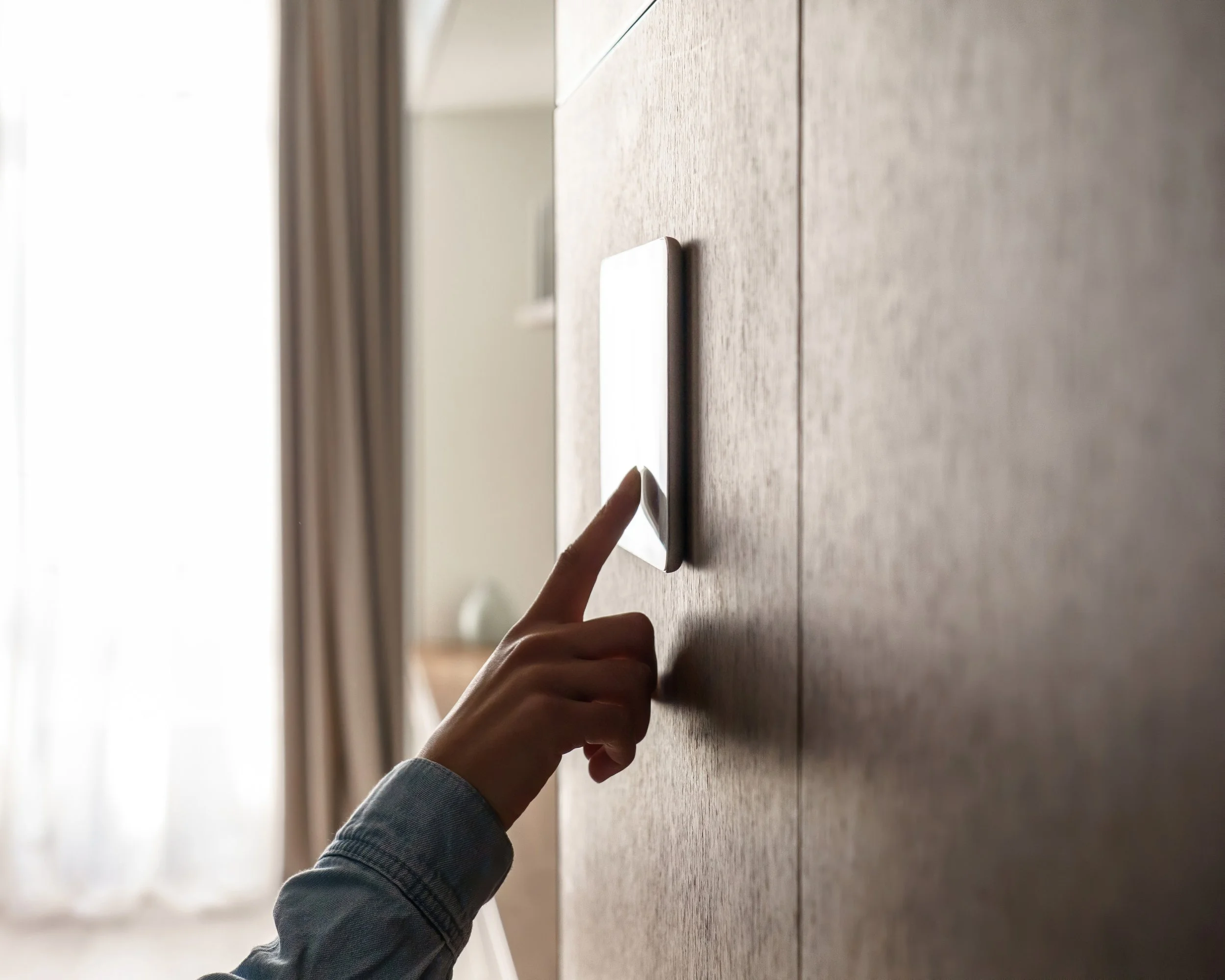 A person pressing a touch screen control system on a wooden wall.