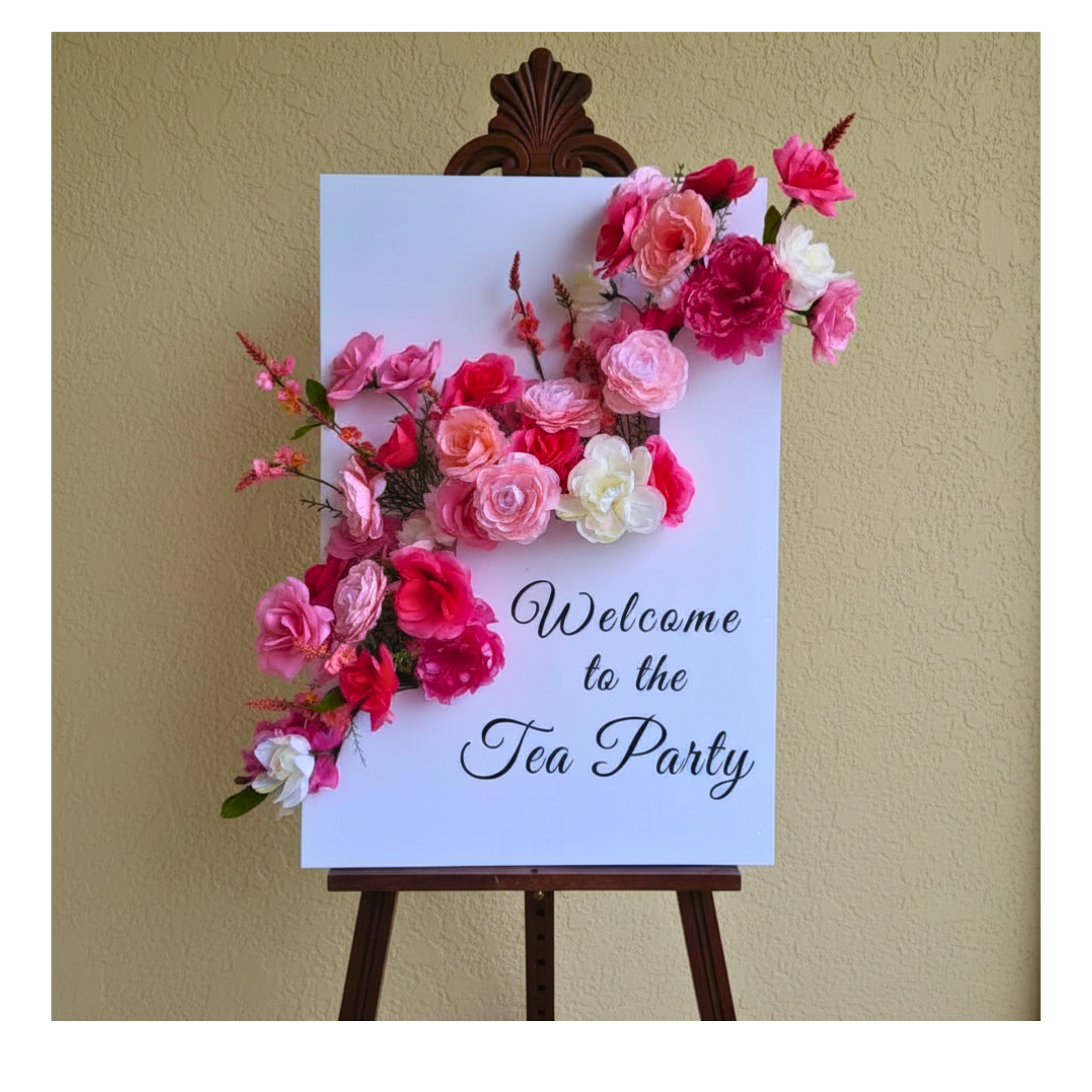 Handcrafted foam board welcome sign featuring silk flowers installation in shades of pink, blush, fuchsia, and white, created as a statement entrance display for a tea party celebration.