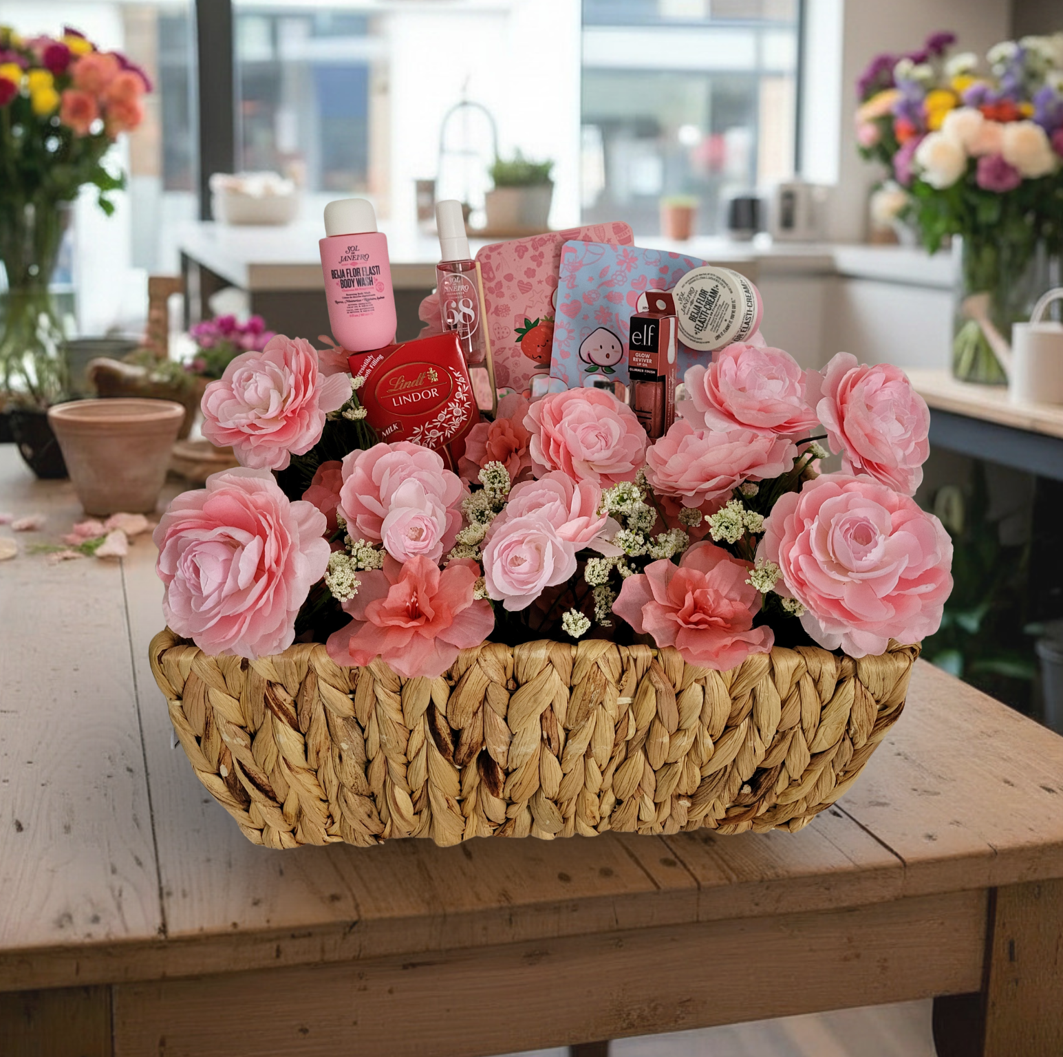Pink bloom basket arrangement featuring flowers and curated gift items in a basket