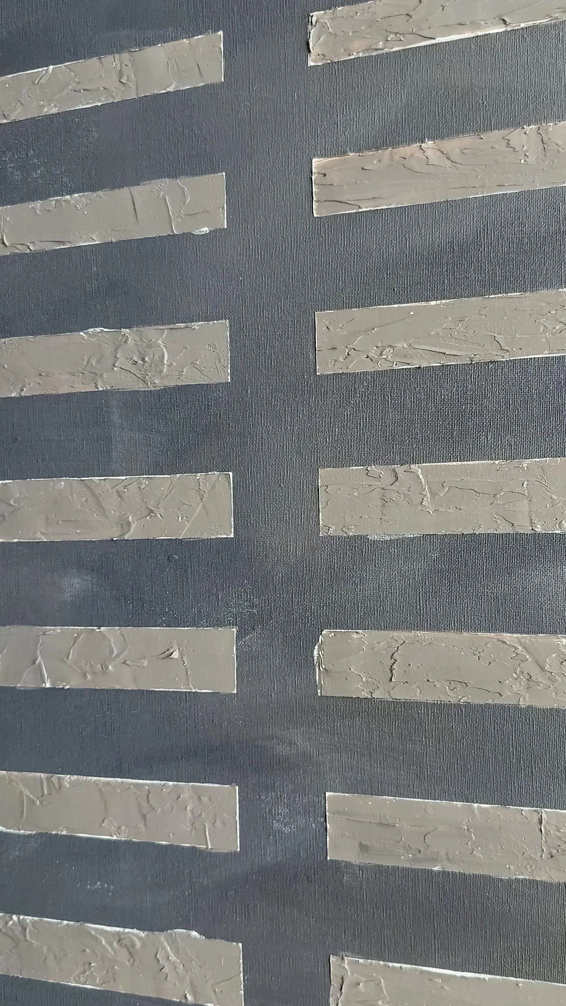 Close-up of a wall with horizontal decorative strips, dark gray background, textured surface, and light gray wood grain pattern on the strips.