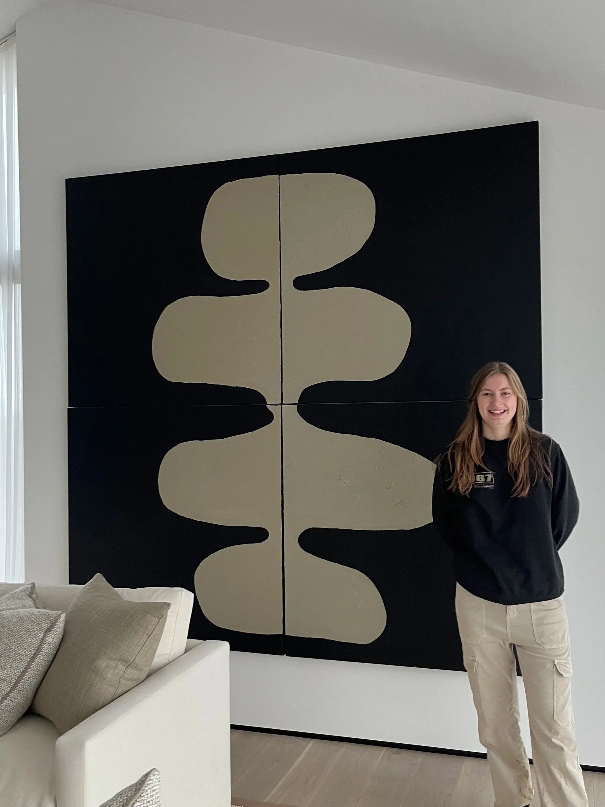 Large black and cream abstract painting above a cream sofa